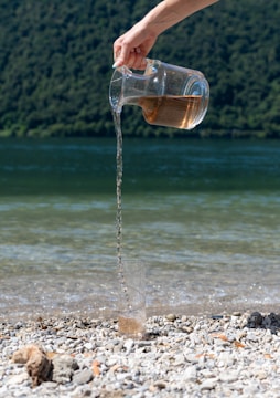 Water is poured from a jug onto the beach.