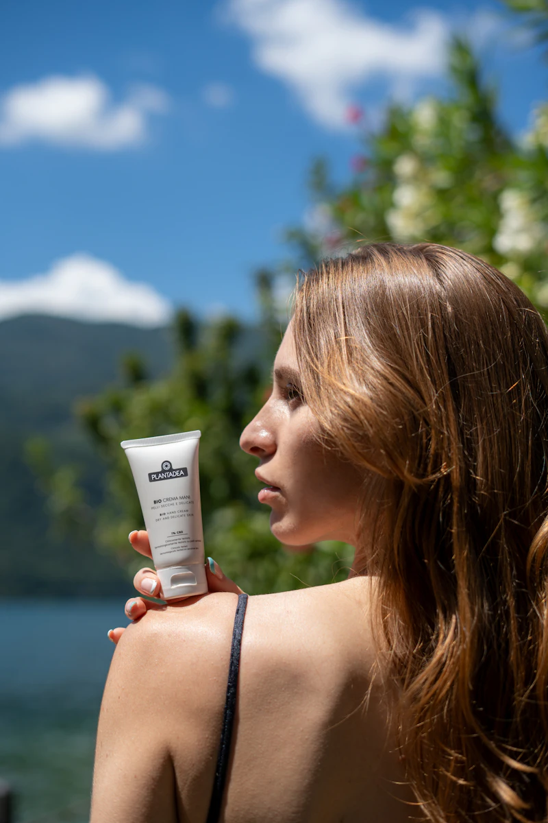 Person holding a tube of sunscreen in the sun