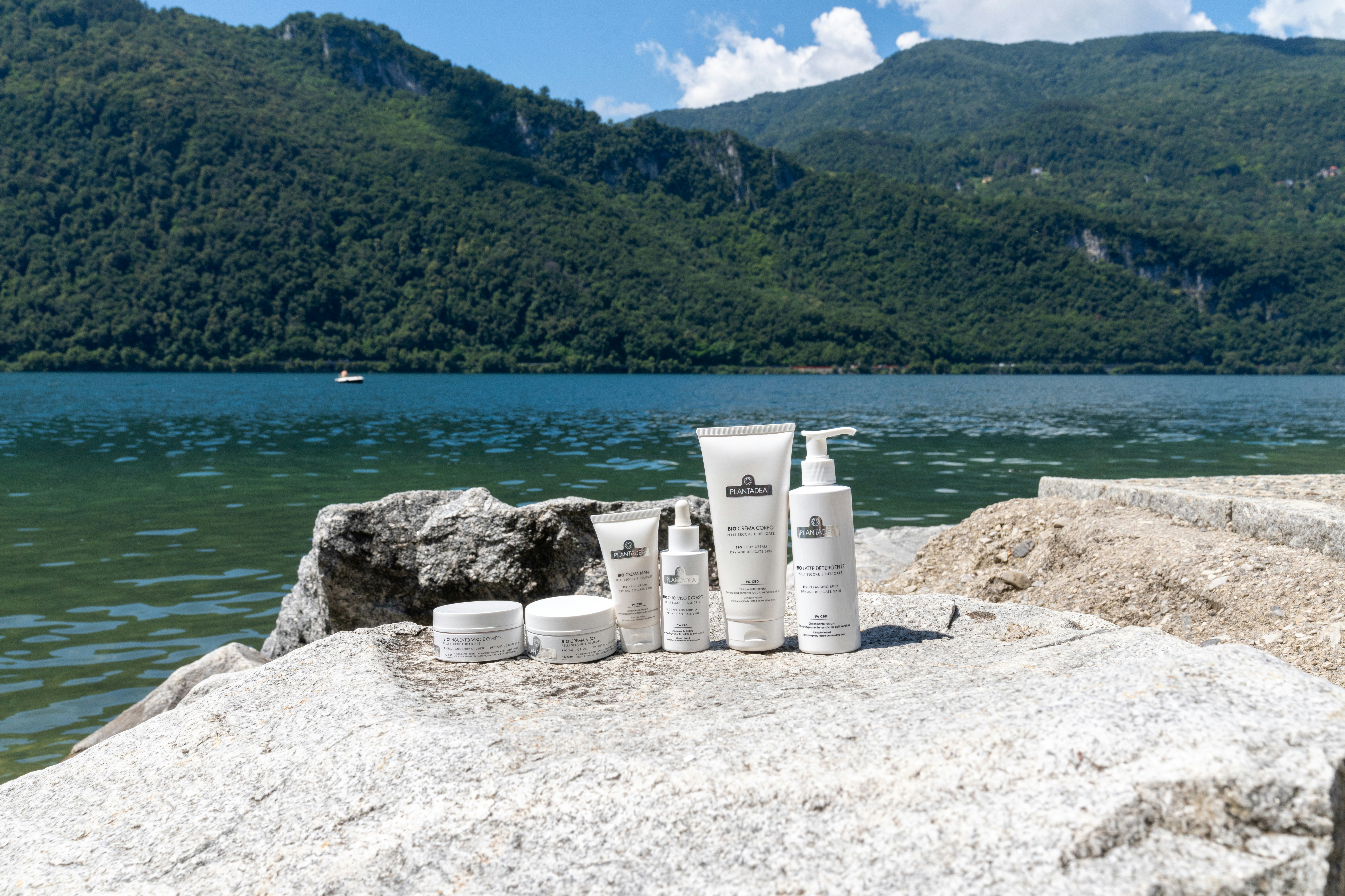 Skincare products sit by the lake with mountains.