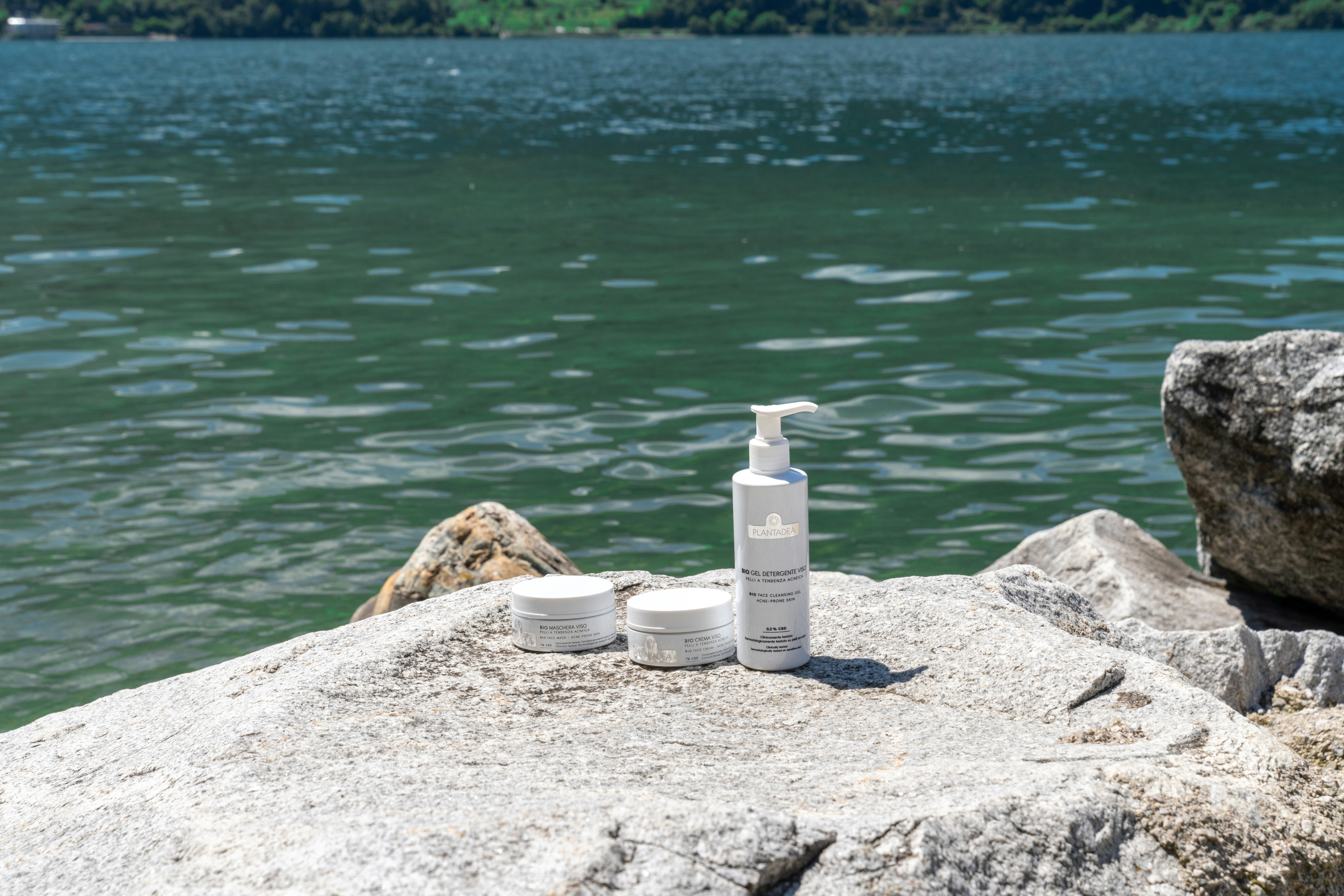 Cosmetics are displayed on a rock by the water.