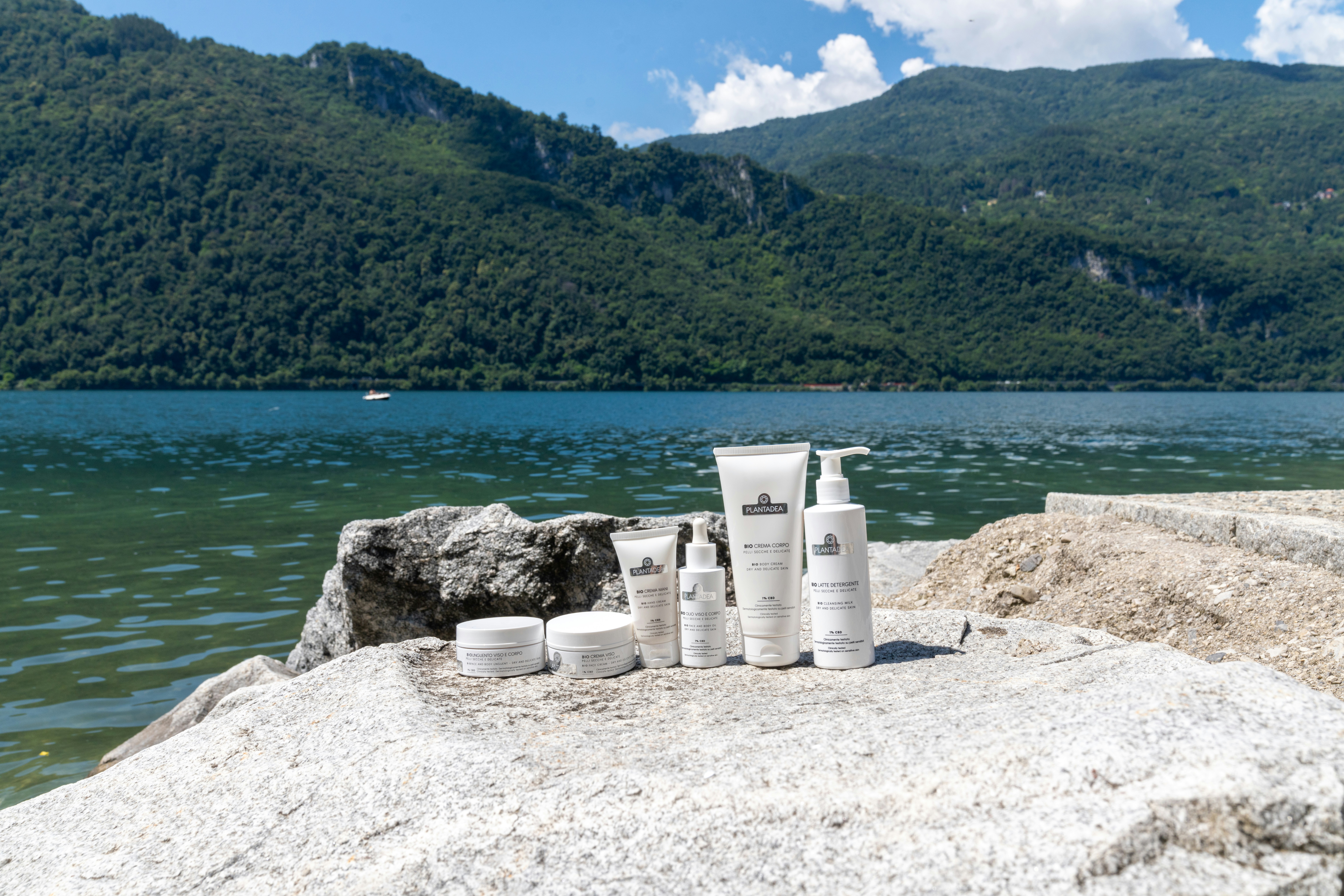 Skincare products are displayed by a scenic lake.