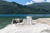 Skincare products are displayed by a scenic lake.