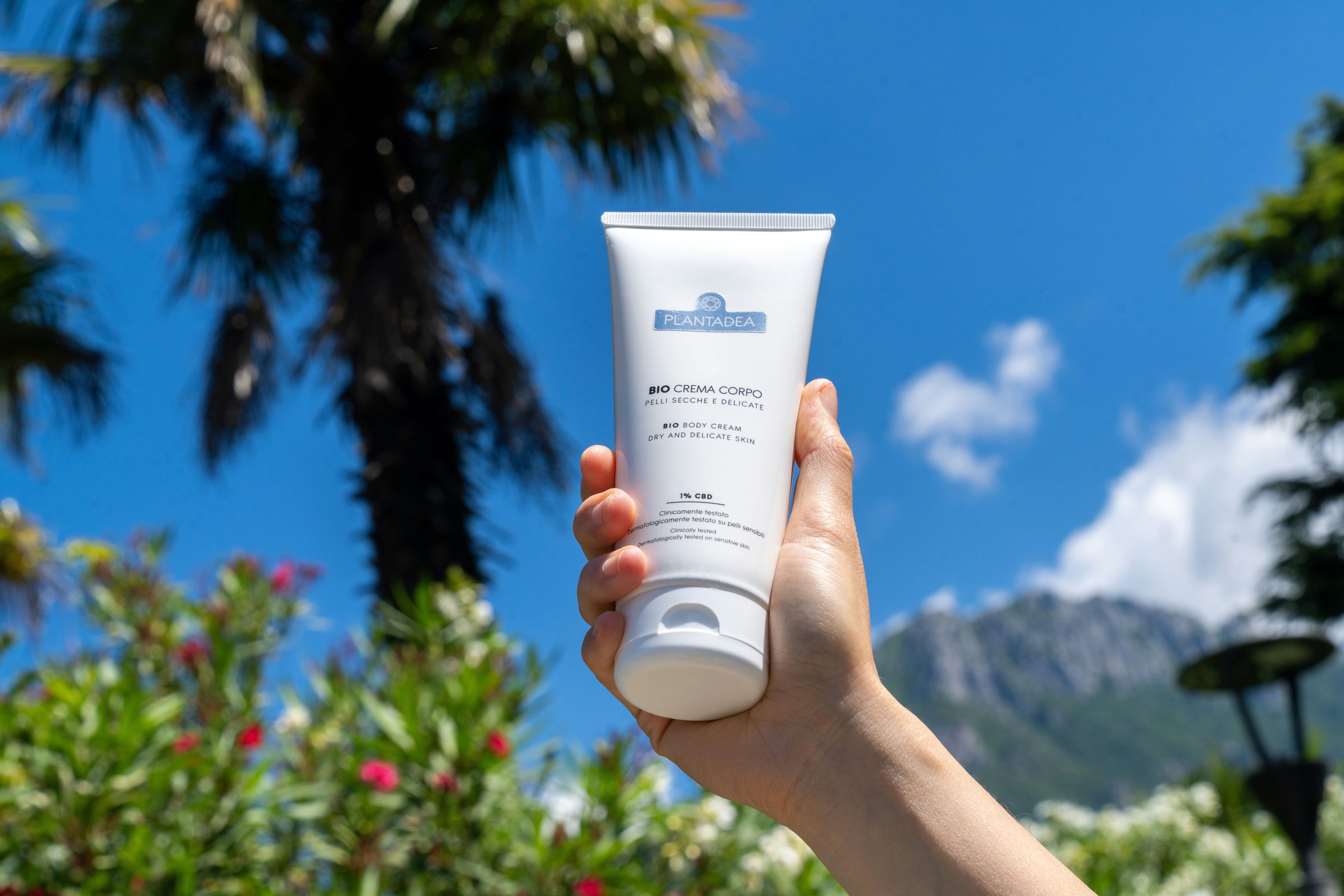 Hand holding a sunscreen tube under the sun.