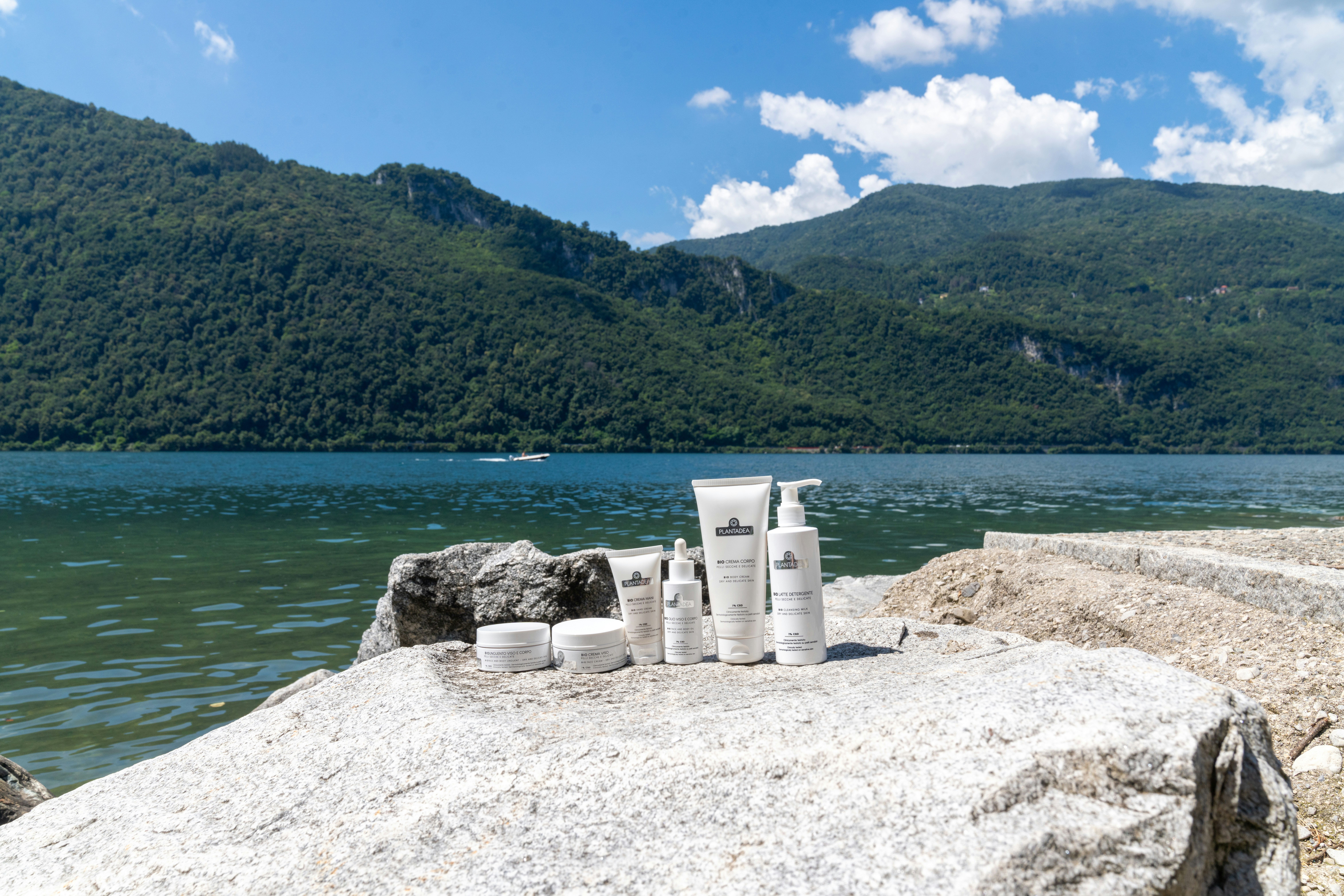 Skincare products are displayed by a lake.