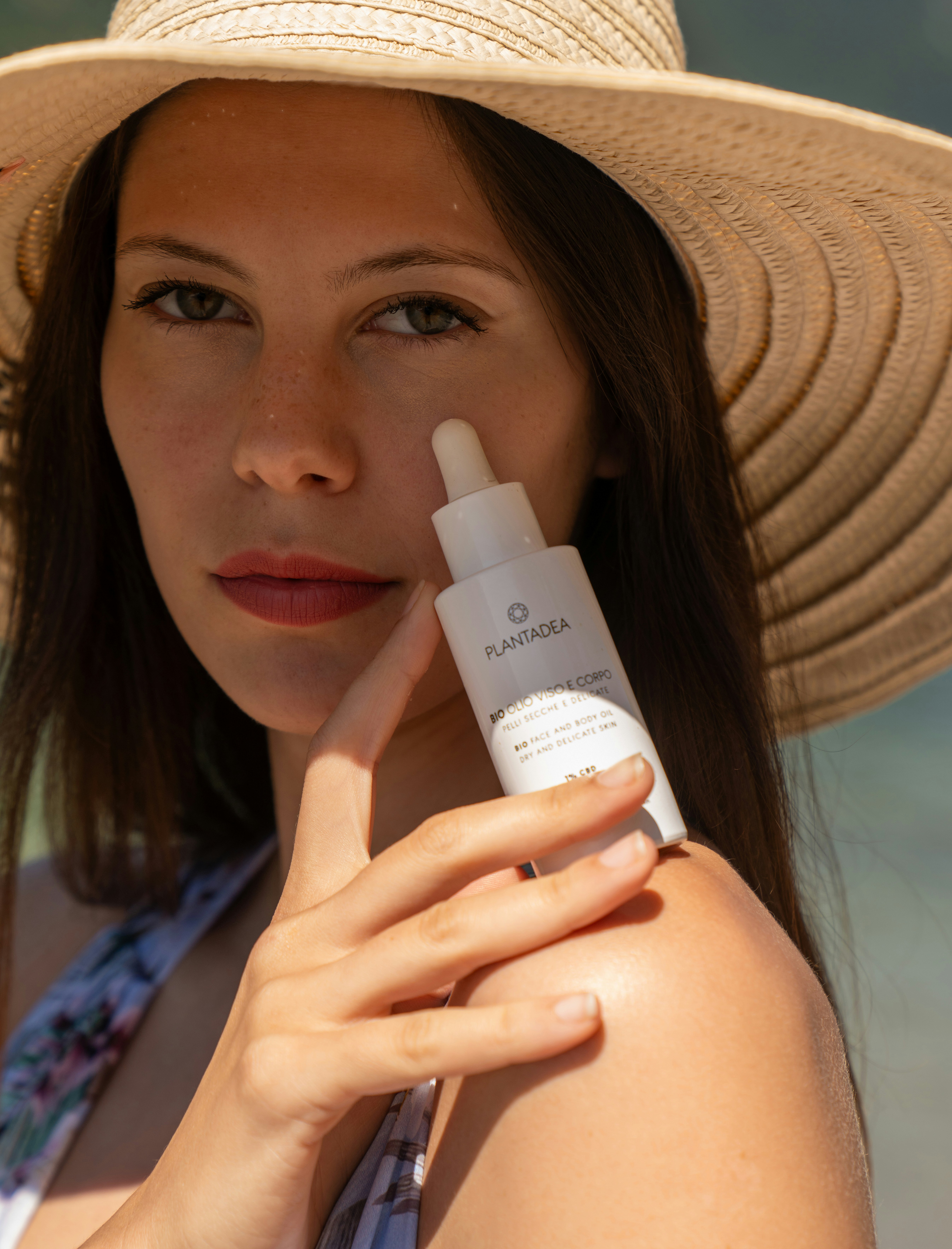 Woman with serum bottle, posing by the water.