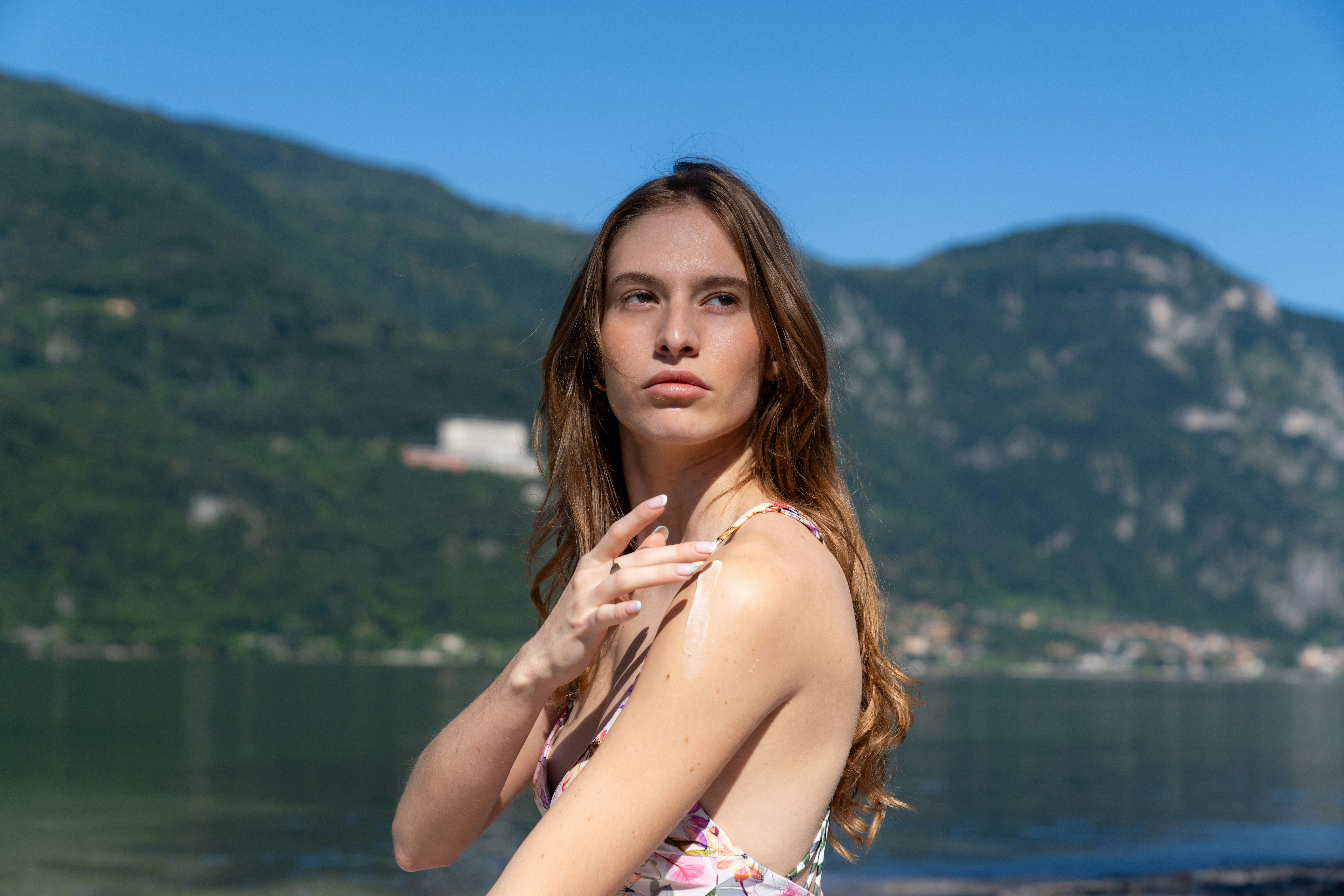 Woman poses near a lake with mountains in the background