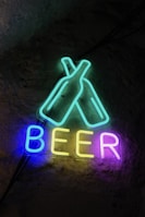 Neon sign says "beer" with beer bottles.