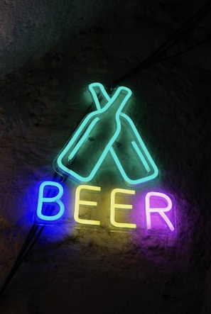 Neon sign says "beer" with beer bottles.