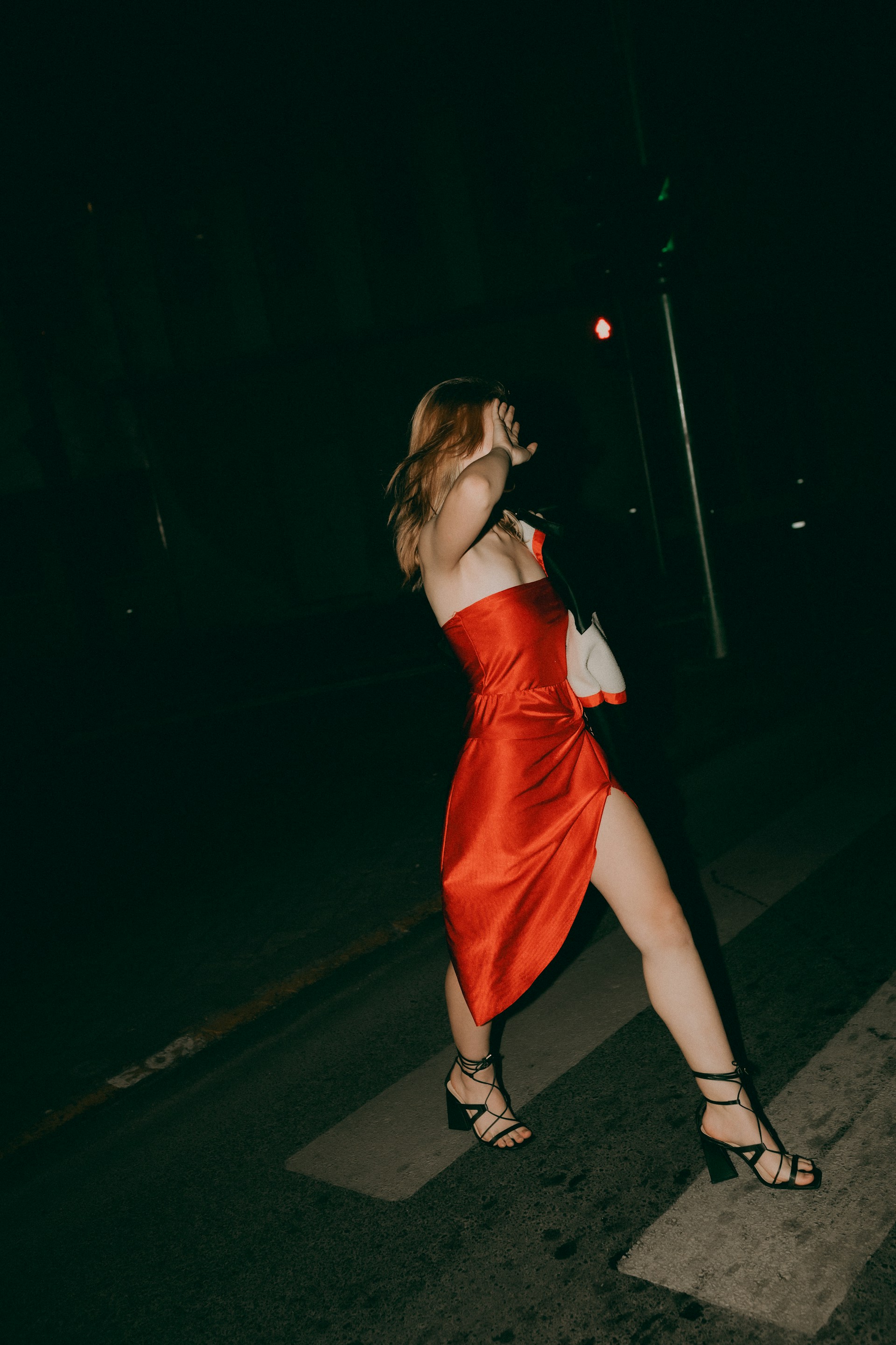Woman in red dress walks at night.