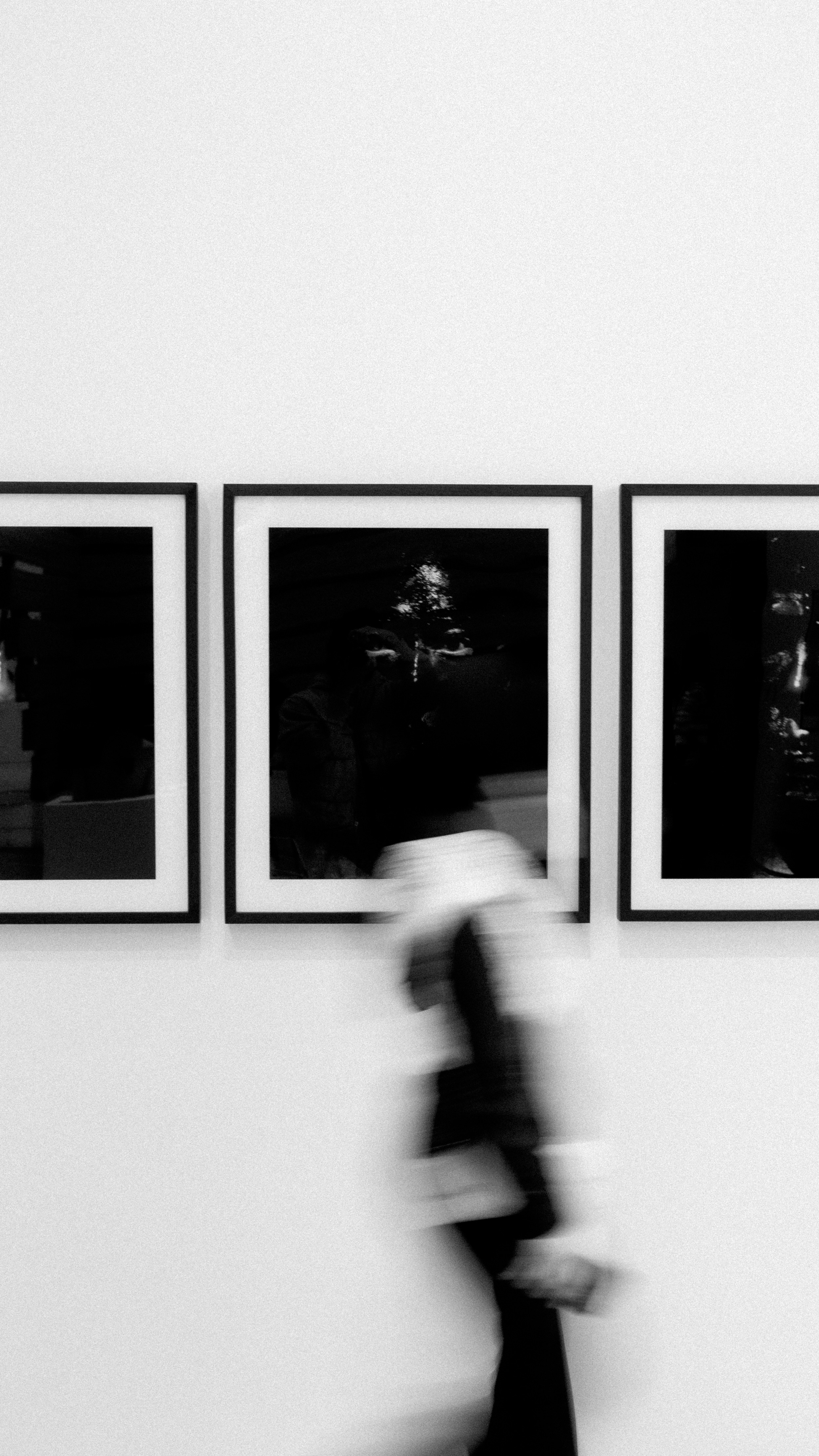 Person walks past framed art in black and white.