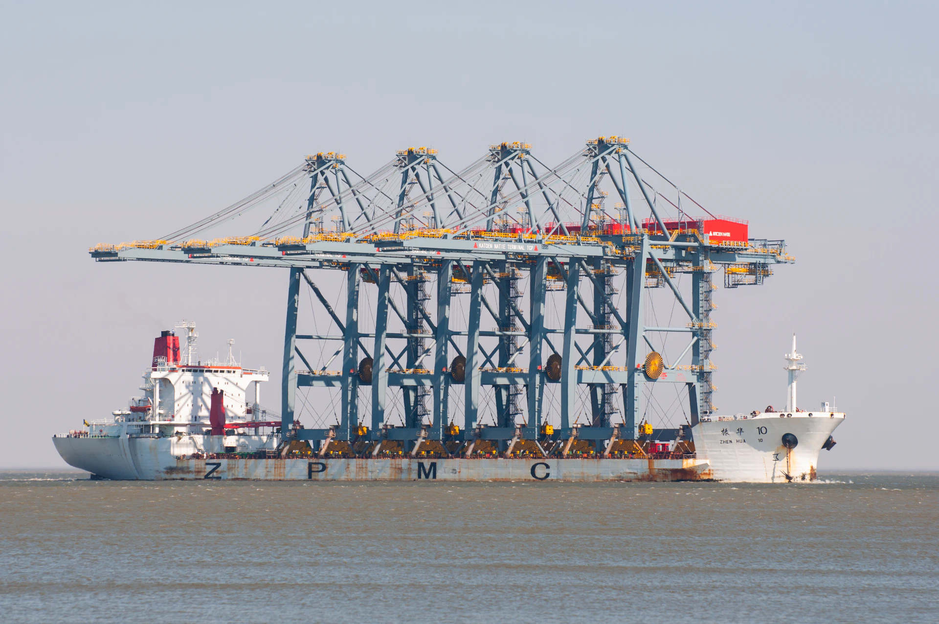 A ship carries large cranes at sea