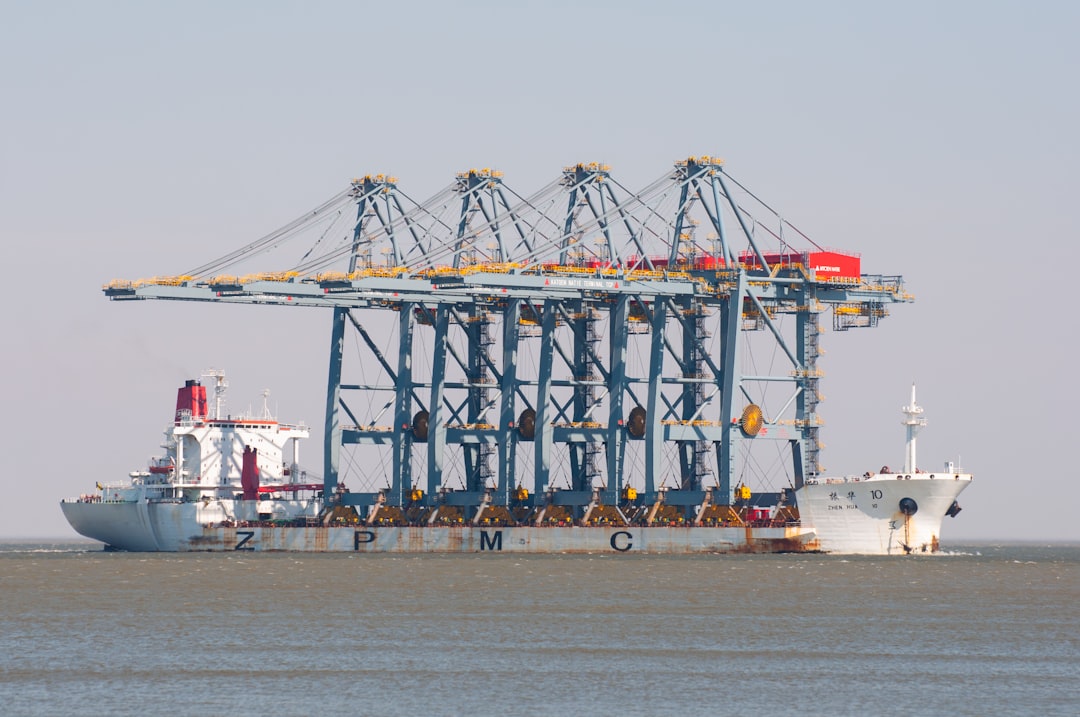 A ship carries large cranes at sea., The cargo vessel Zhen Hua 10 carrying four massive port cranes on its deck, approaching the Port of Montevideo in 2009. A striking image of global trade in motion.