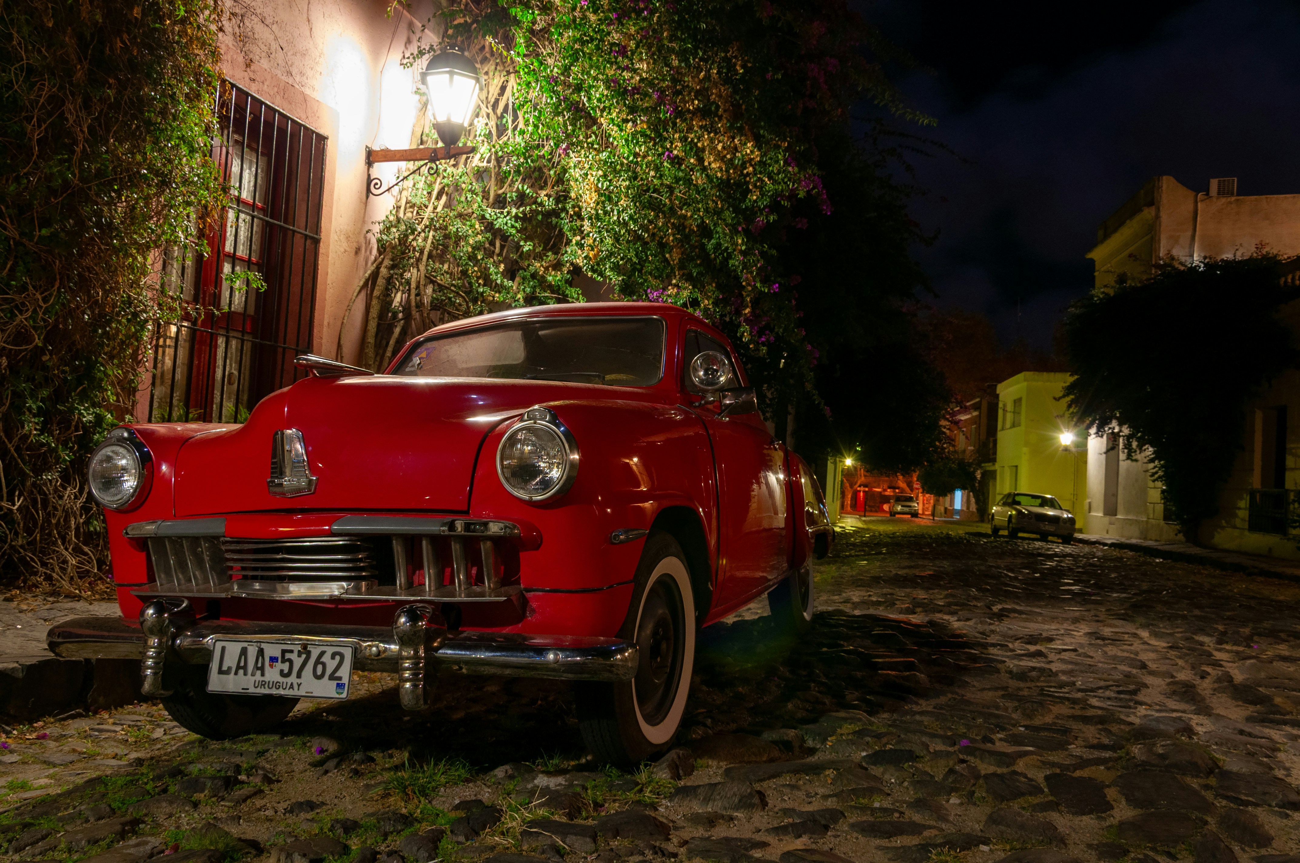 A red vintage car sits illuminated at night.