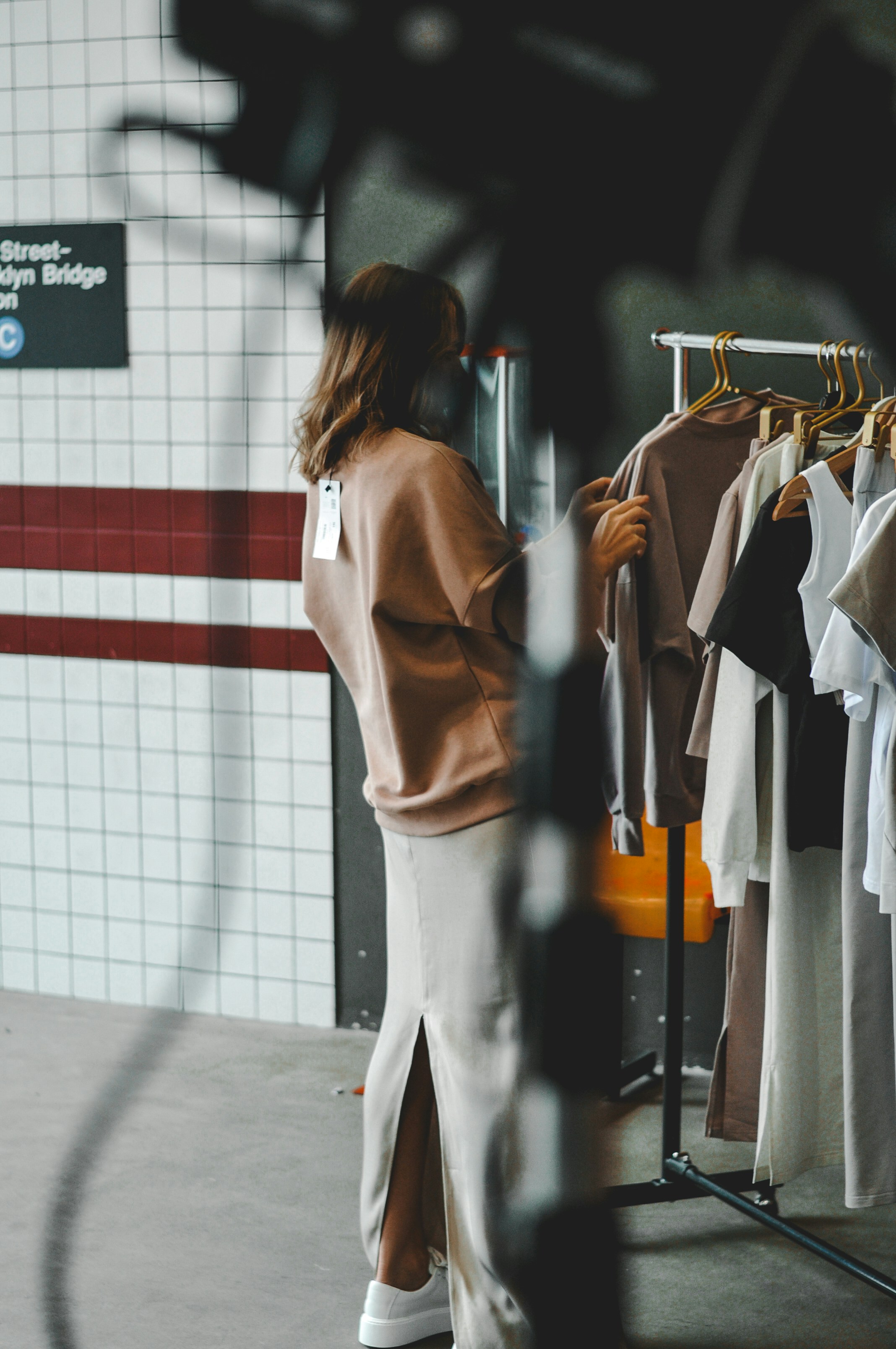 A woman is browsing clothes on a clothing rack.