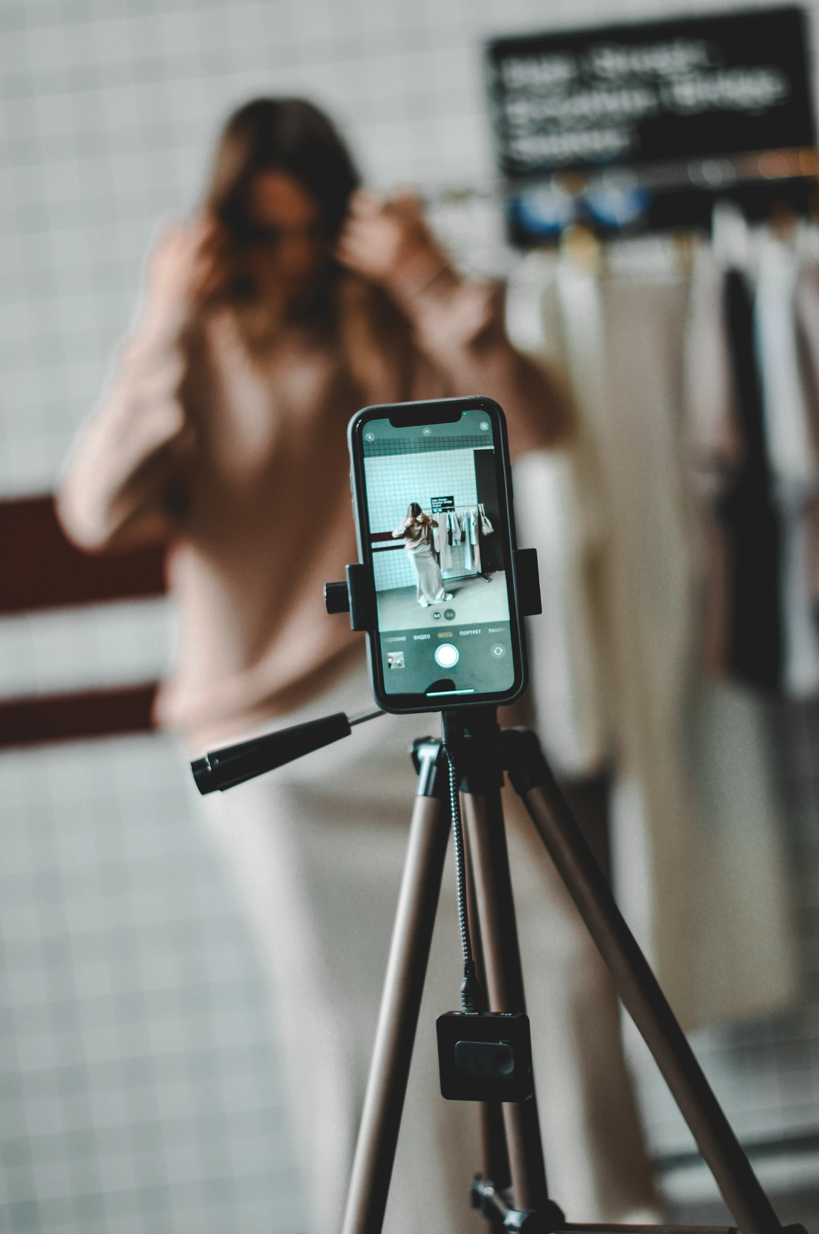 A smartphone on a tripod recording a woman in a softly lit room