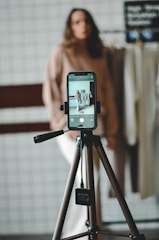 Woman is filming with a smartphone on a tripod.