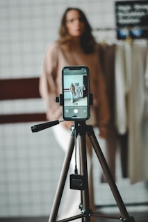 Woman is filming with a smartphone on a tripod.