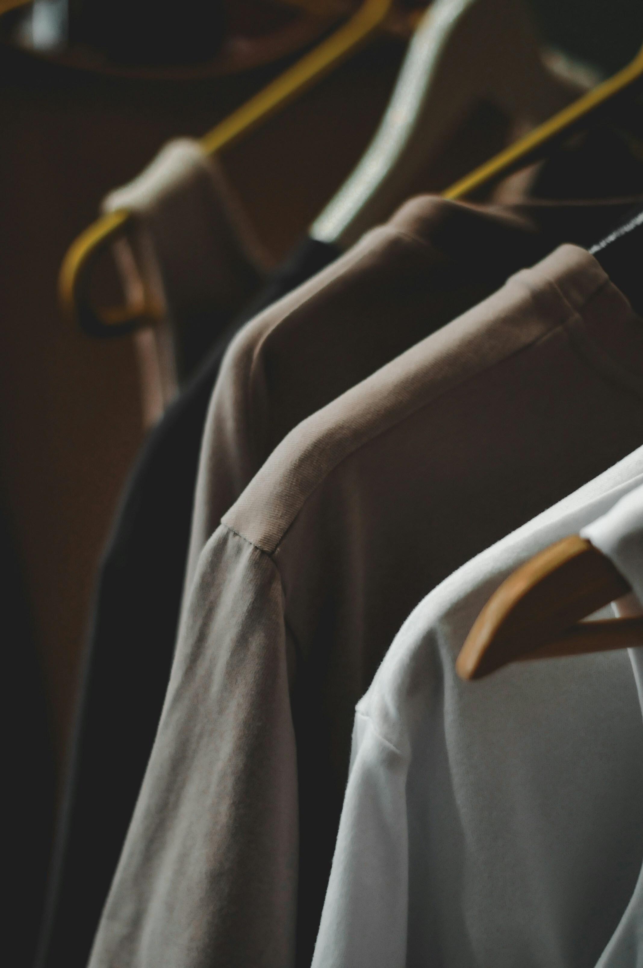 Shirts on hangers in various neutral colors.