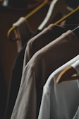 Shirts on hangers in various neutral colors.