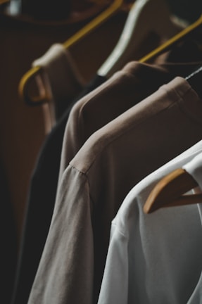 Shirts on hangers in various neutral colors.