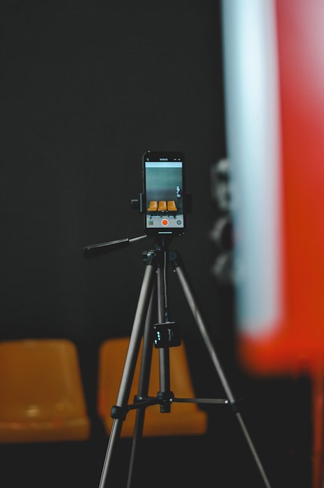 A smartphone mounted on a tripod films a product for a shoppable video, representing DIY on-site video production.