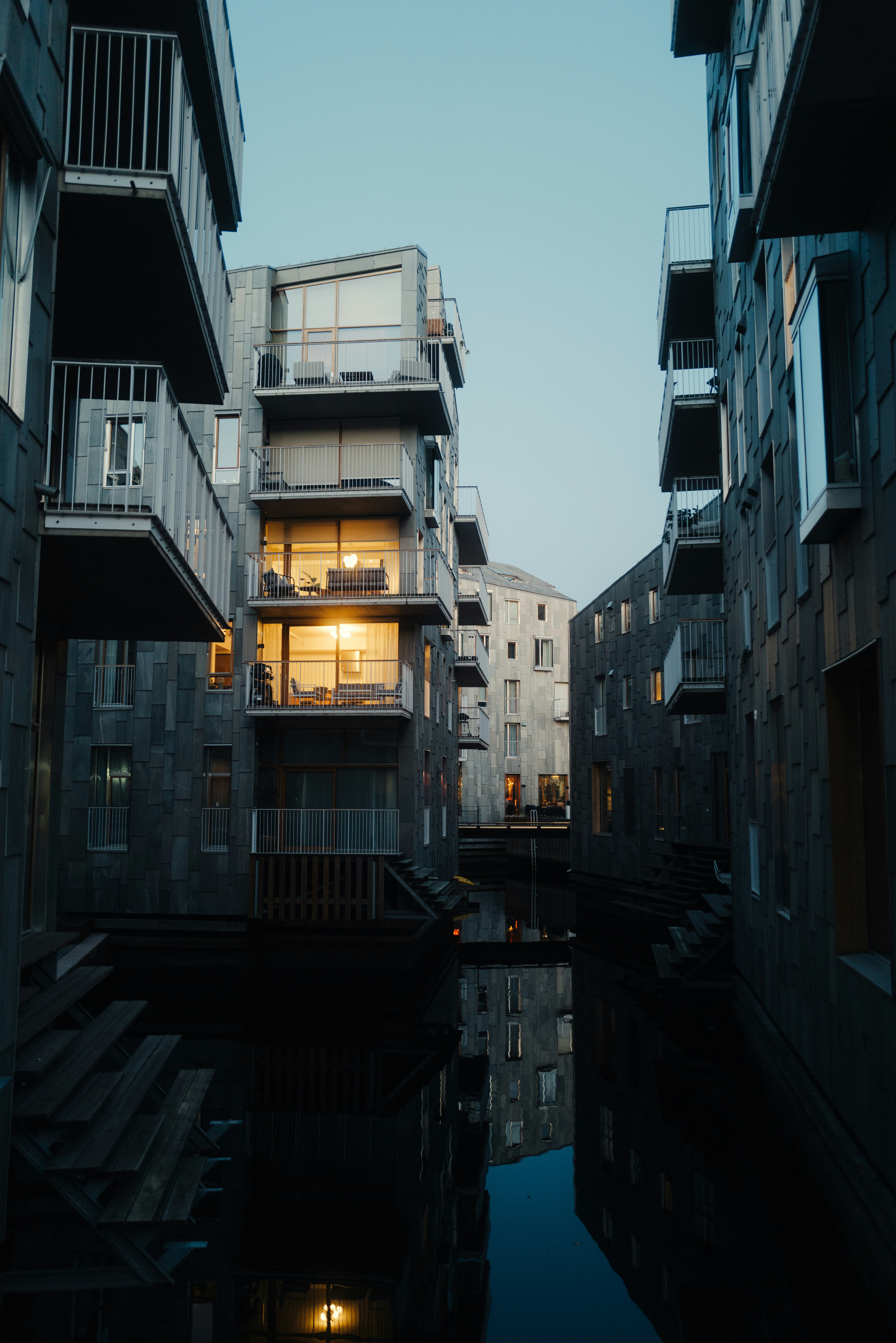 Buildings with lit windows reflect in dark water.