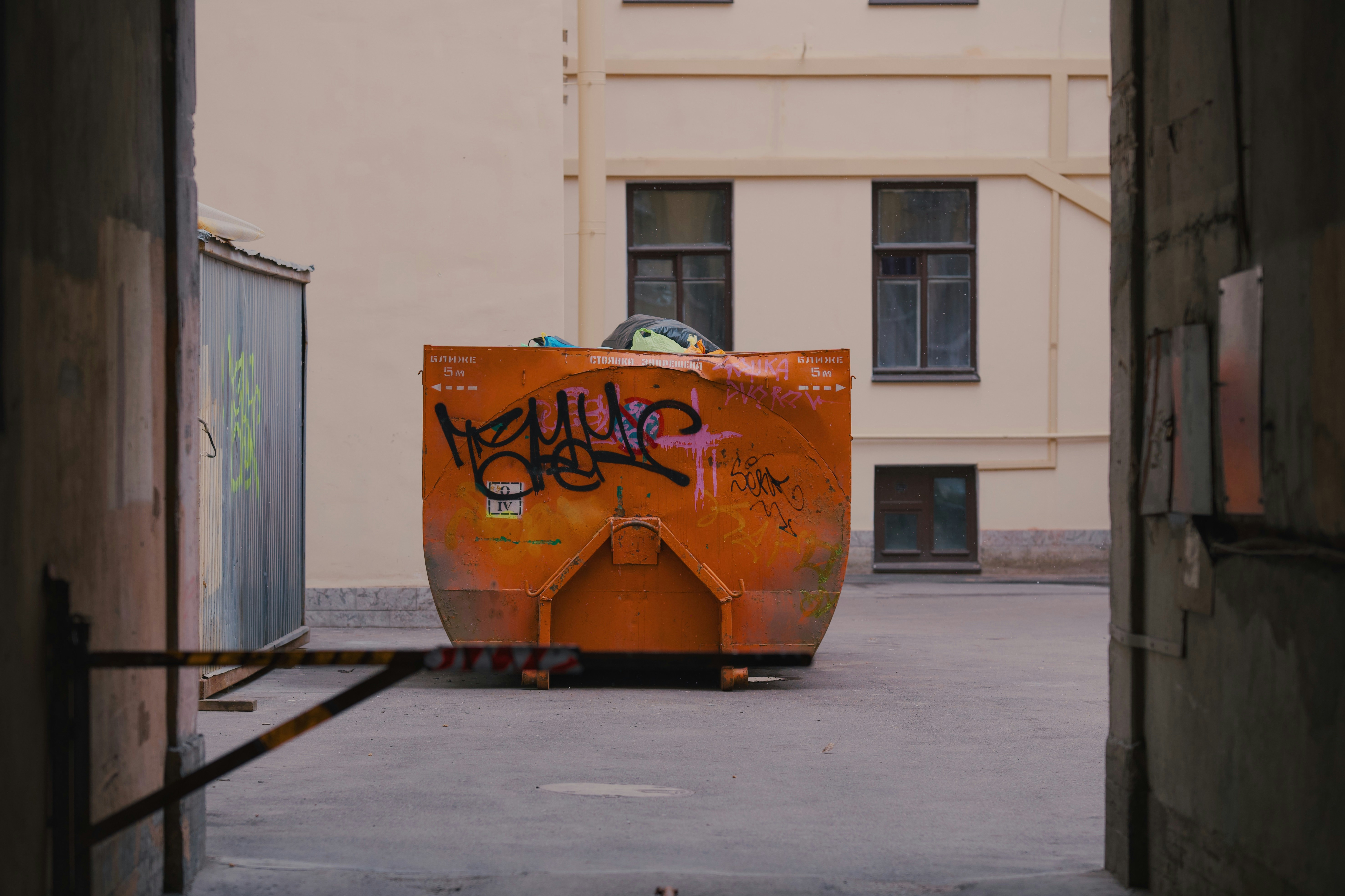 An orange dumpster in an urban alley.