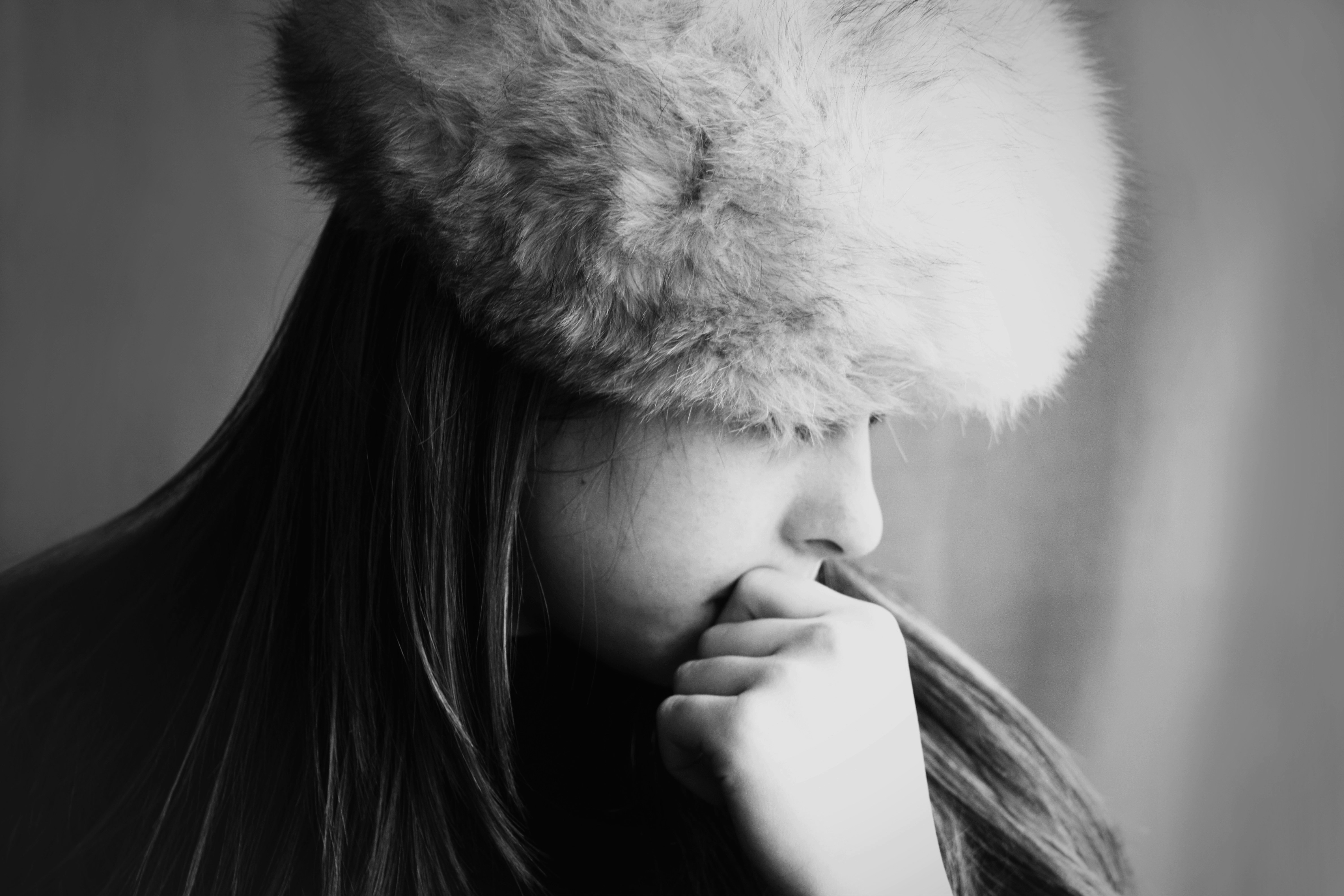 A woman in a fur hat looks thoughtful.