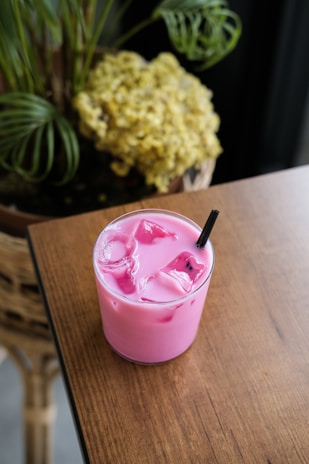 Pink drink with ice and a straw.