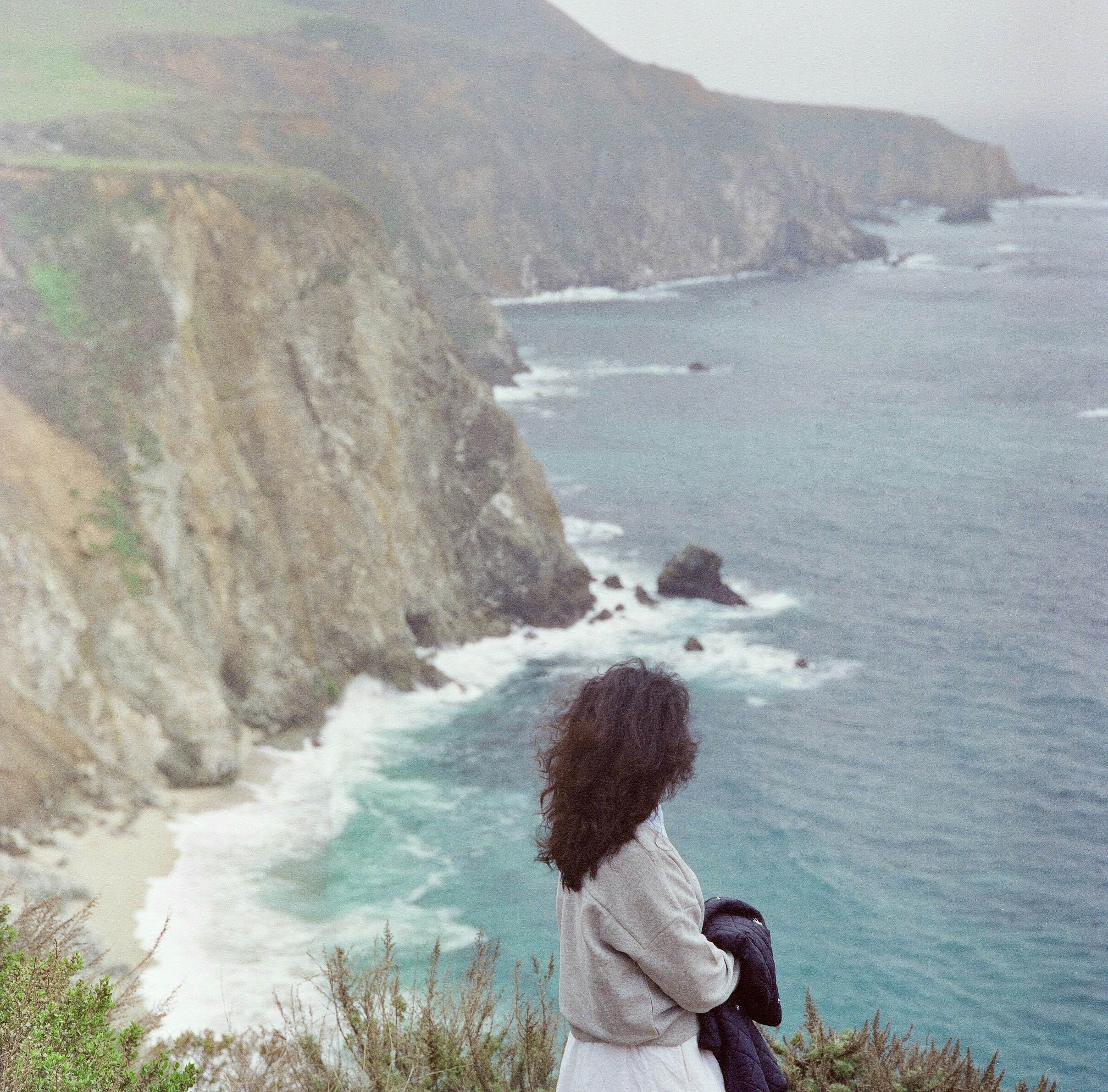 Woman enjoys view of ocean from cliffs.