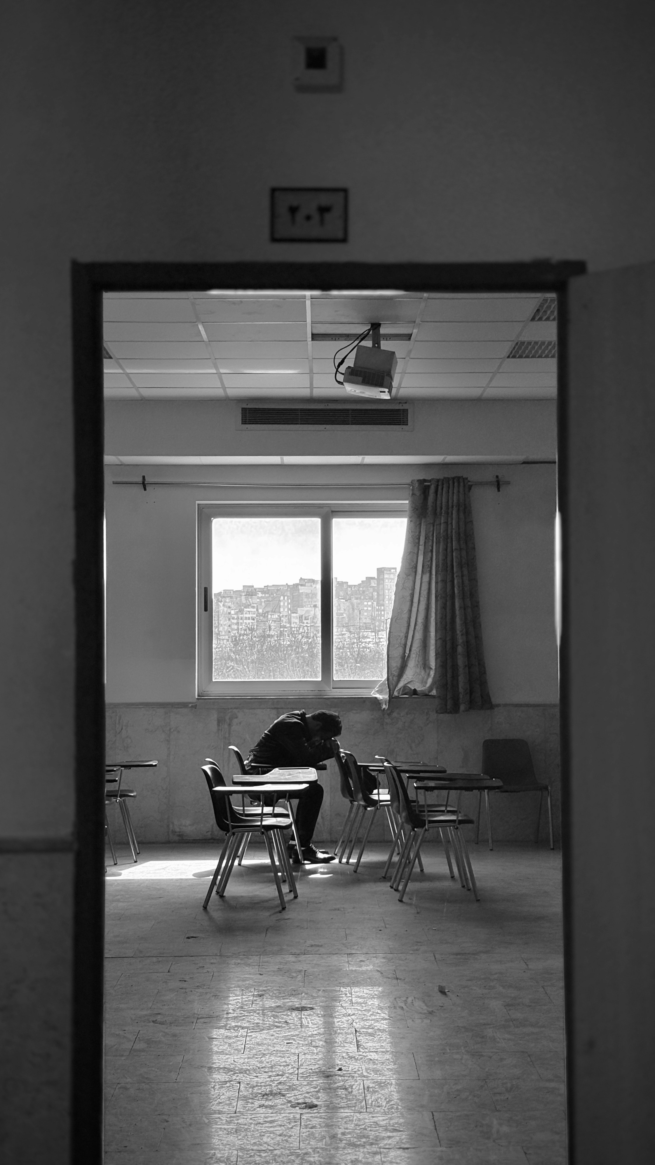 A person slumps over at their classroom desk.