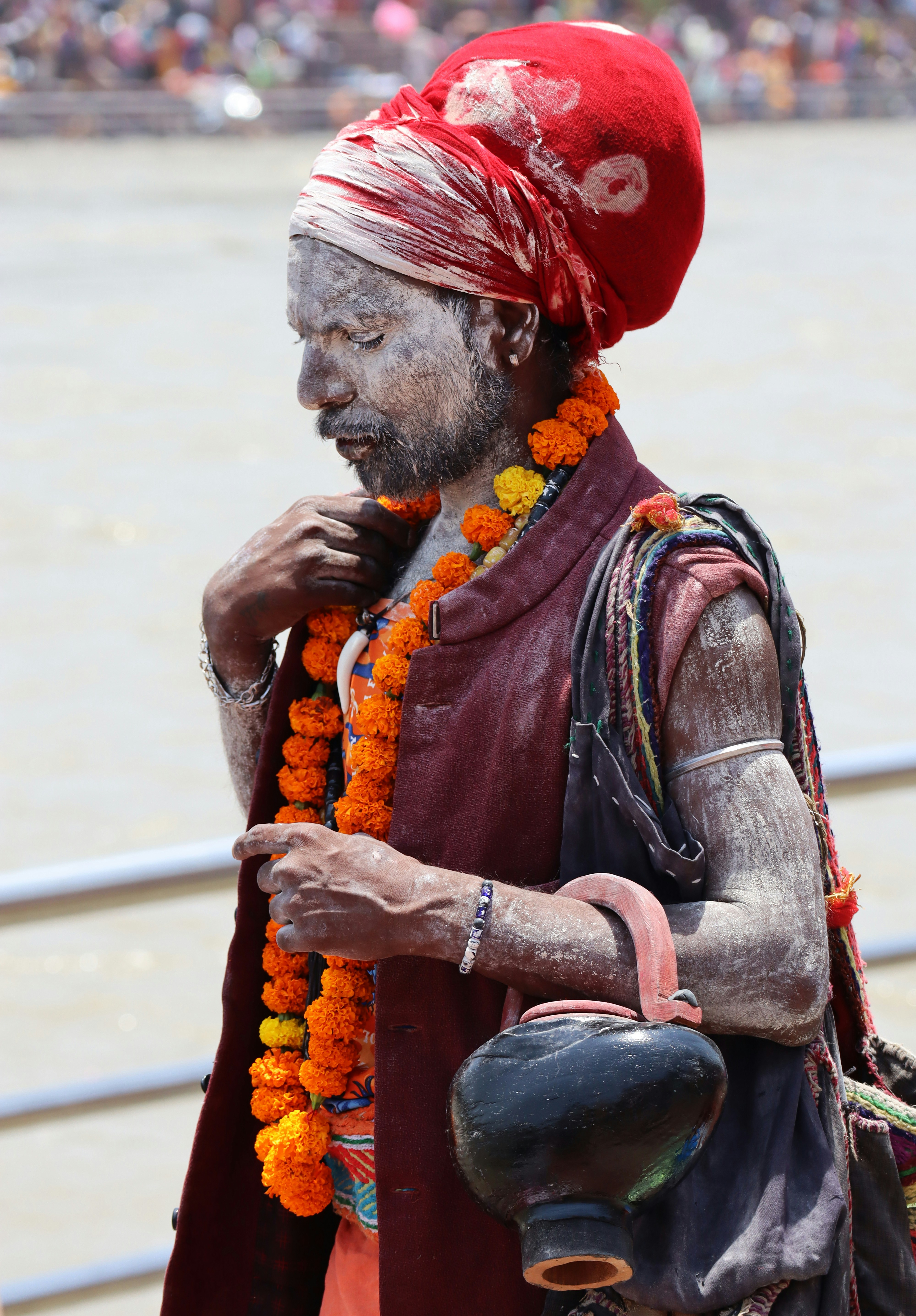 A sadhhu stands with marigold and a pot.