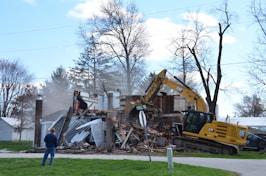 A house is being demolished by a backhoe.