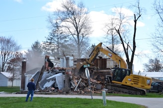 A house is being demolished by a backhoe.