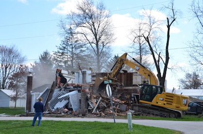 A house is being demolished by a backhoe.