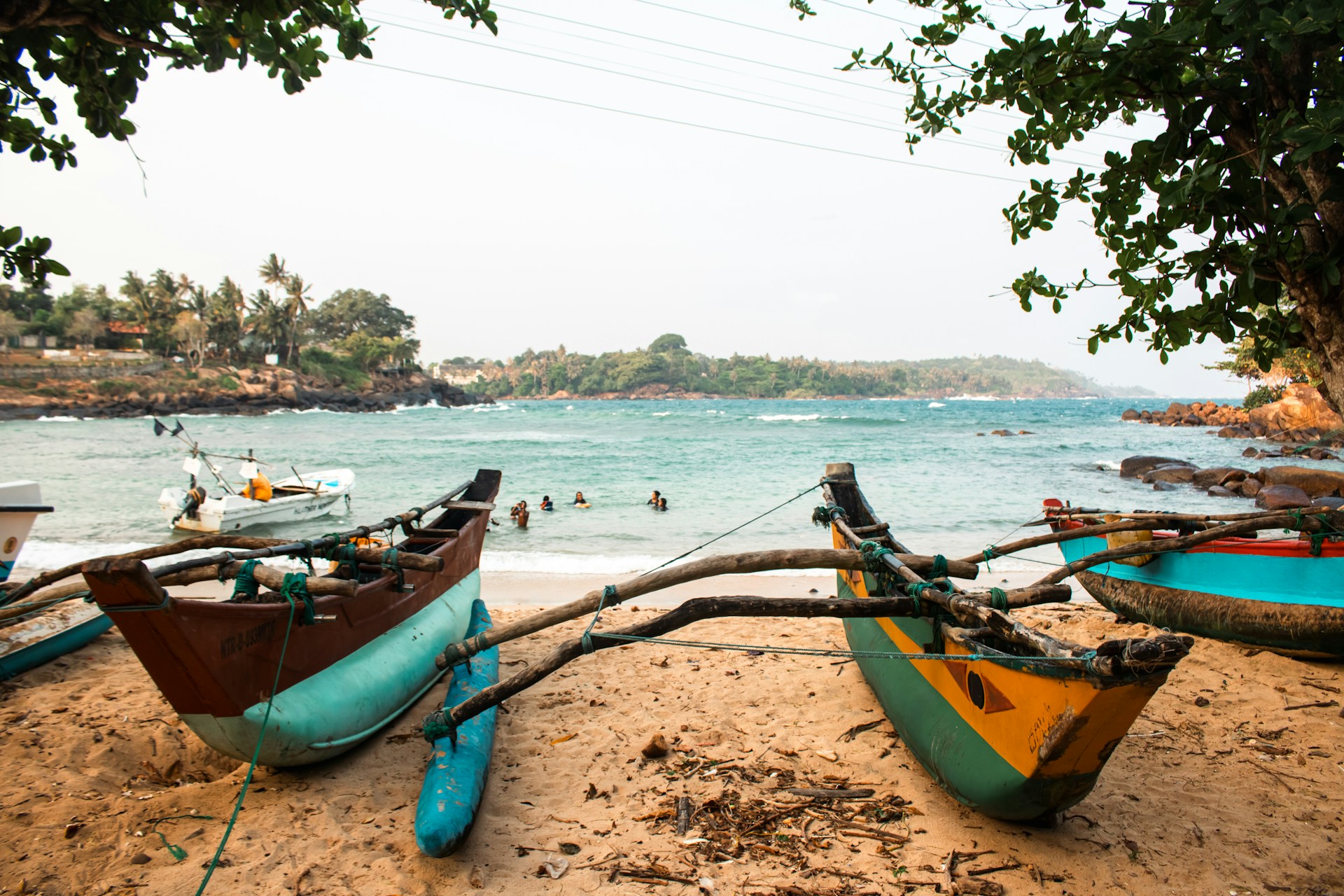 Boats sit on a beach with the ocean in the background.