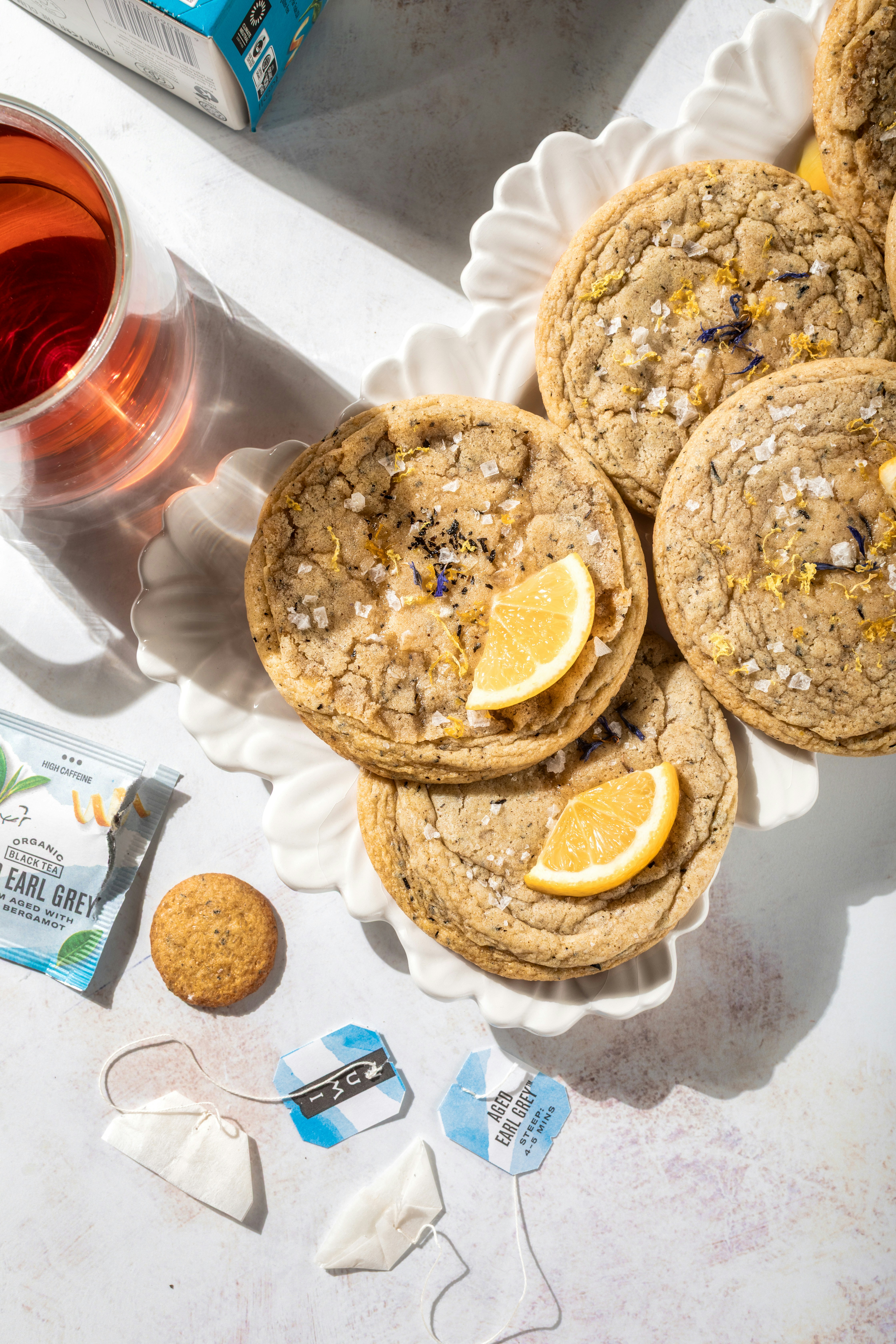 Galletas, rodajas de limón y té en una fuente blanca.