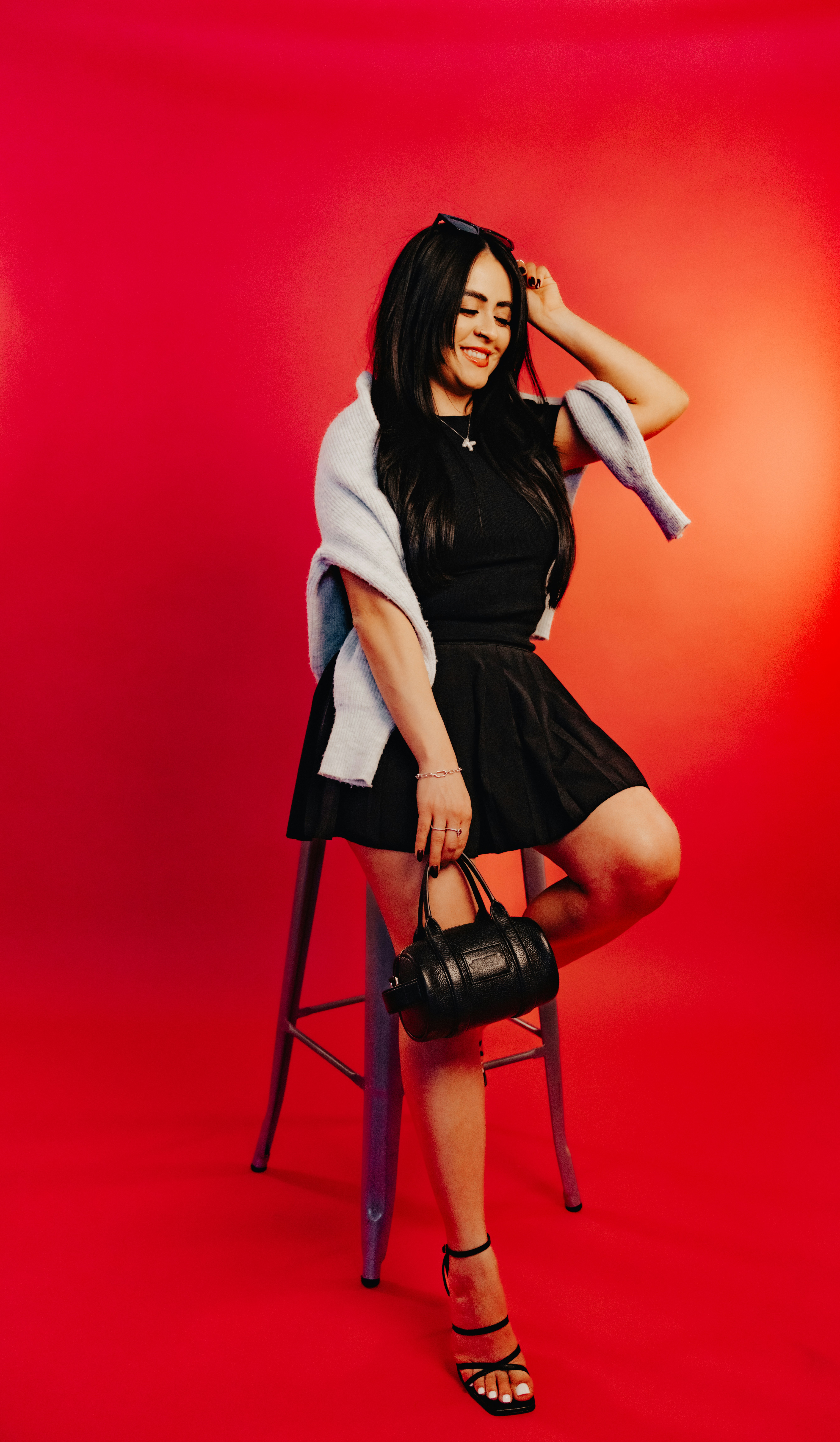A woman poses in front of a red background.