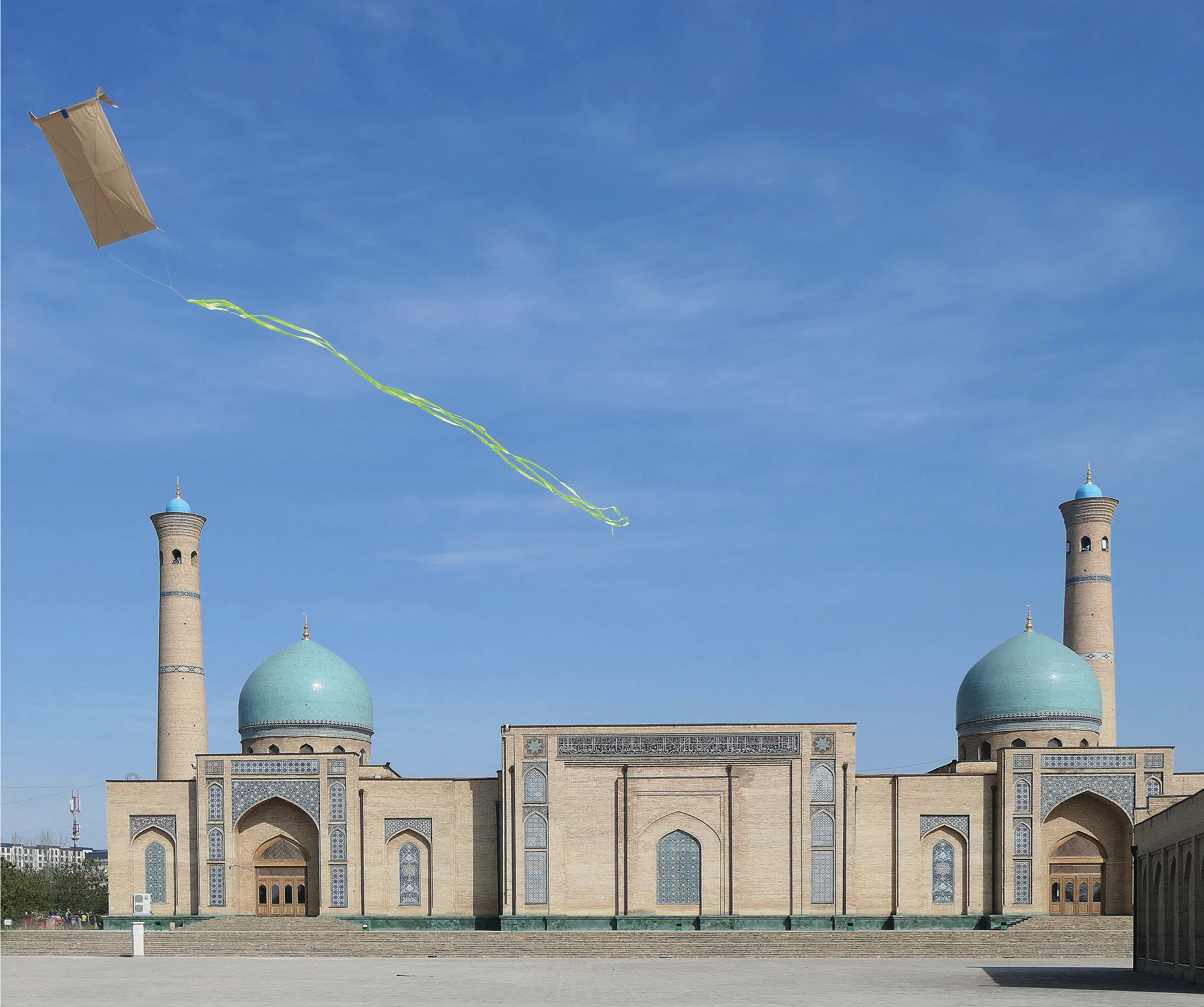 Turquoise domes and minarets of the Hazrati Imam complex in Tashkent, a kite flying over the courtyard