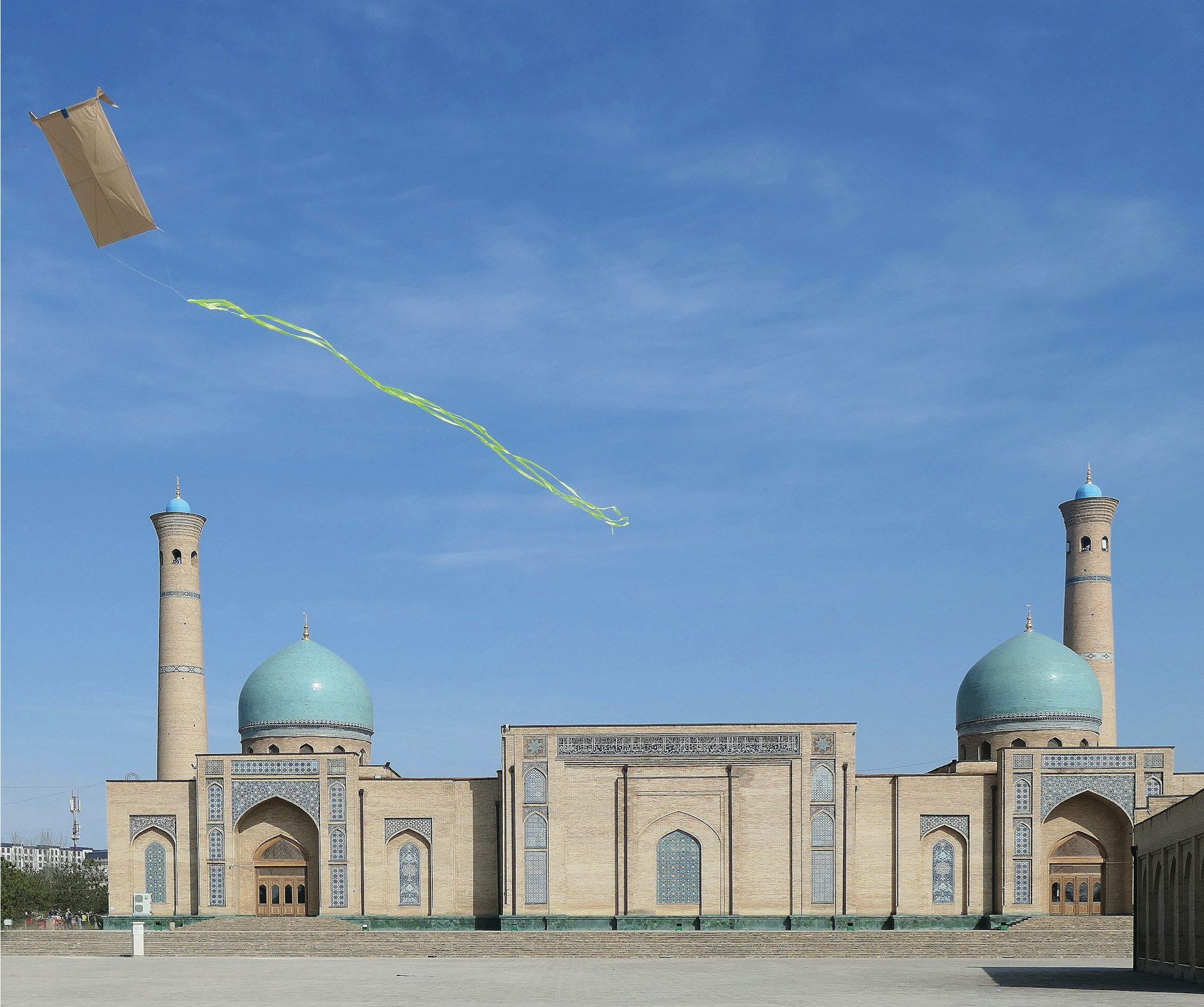 A kite flies above a beautiful mosque.