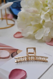 A gold hair claw is placed on a white surface.
