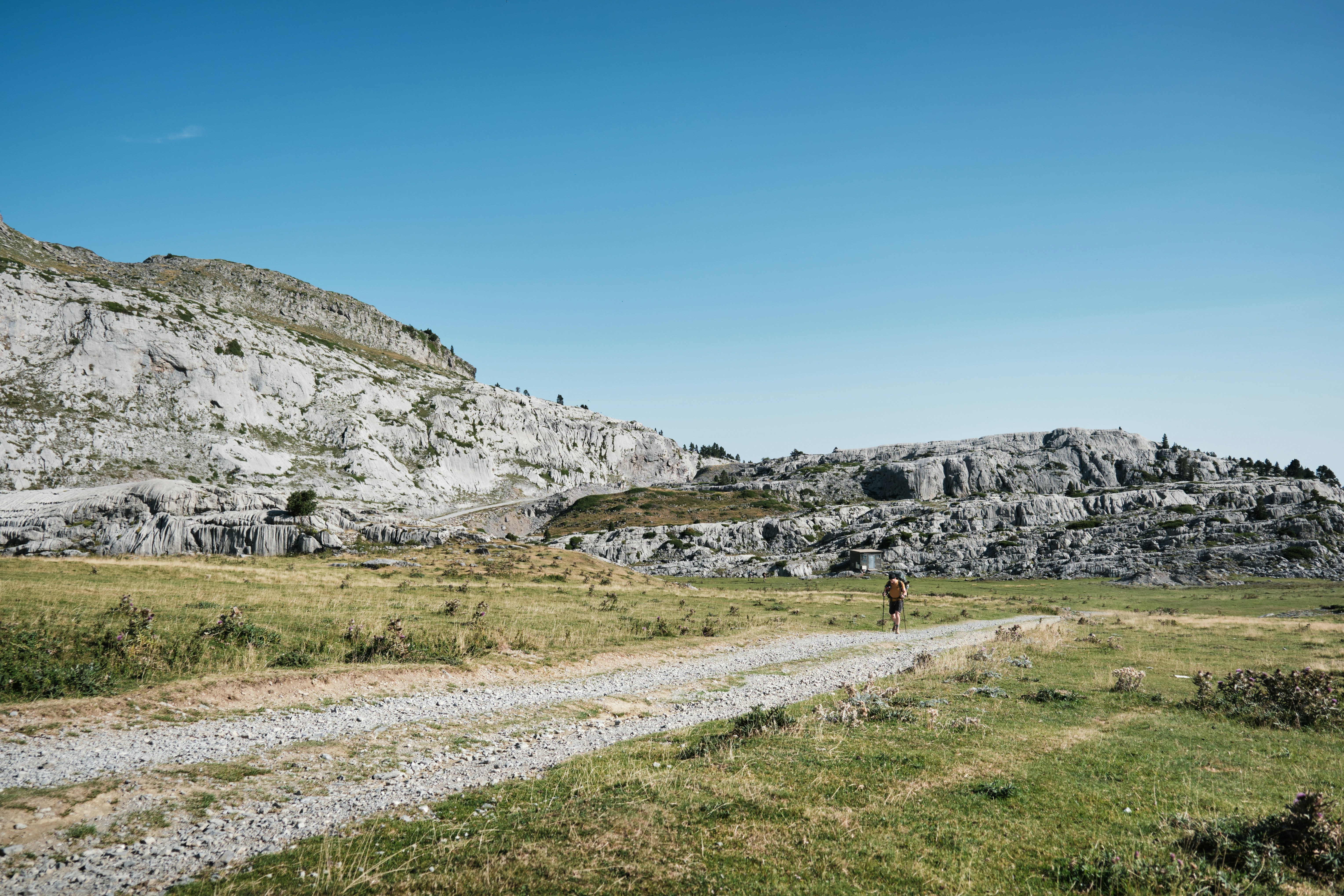 Una persona camina por un sendero cerca de un acantilado rocoso.