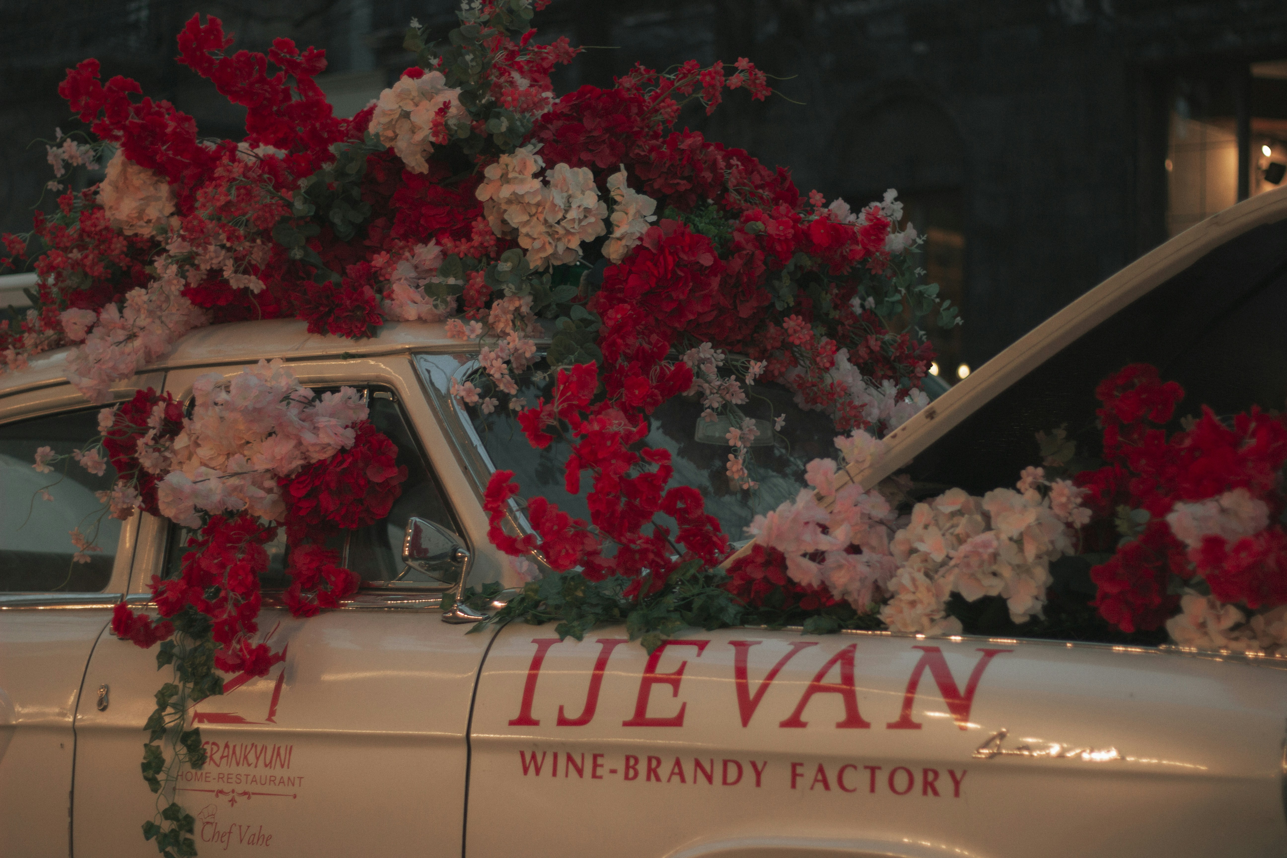 A vintage car decorated with beautiful red flowers.