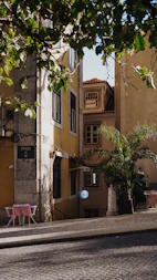 Narrow street with buildings and a small outdoor cafe.