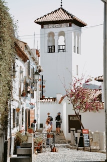 A narrow street leads toward a white tower.