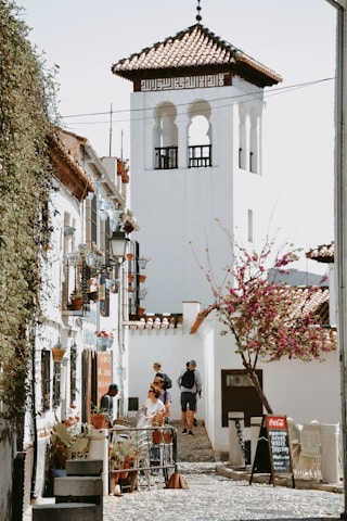 A narrow street leads toward a white tower.