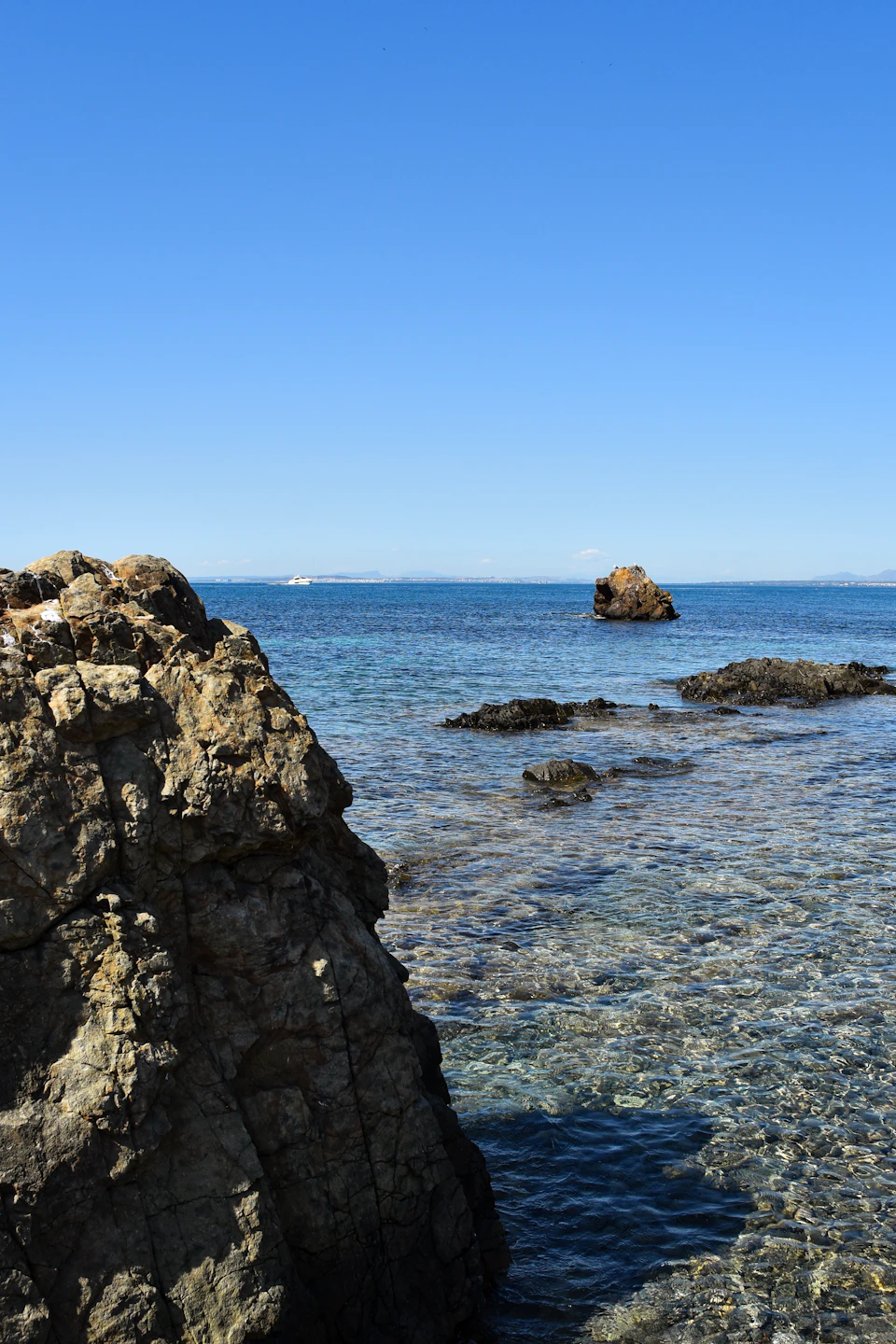 Two large rocks protrude into calm ocean waters with gray and brown hues contrasting sky