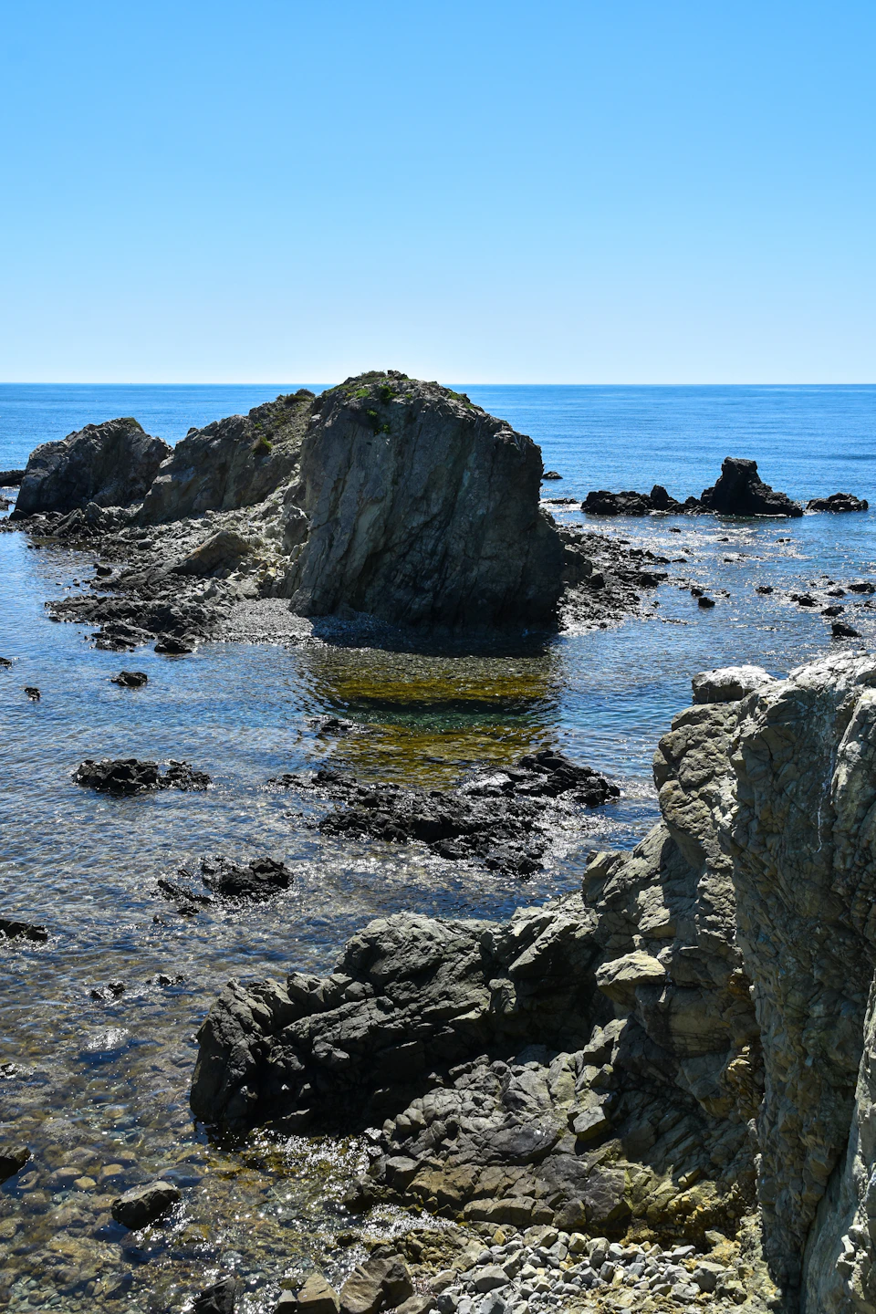 Rocky shoreline with large boulders scattered across the water's edge at low tide