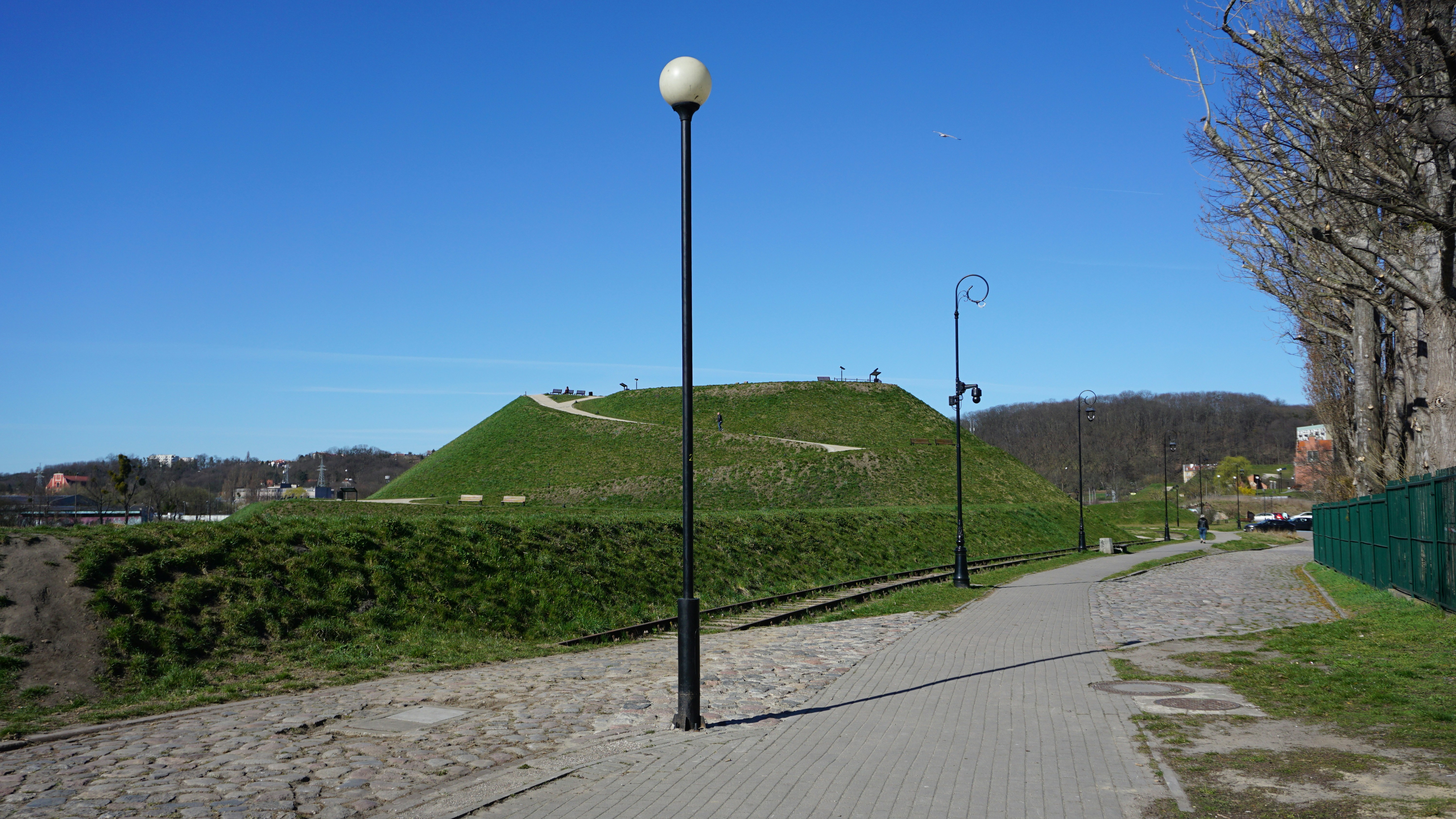 A pathway leads to a green, grassy hill.