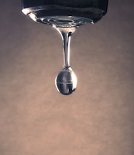 A water drop forms from a faucet.